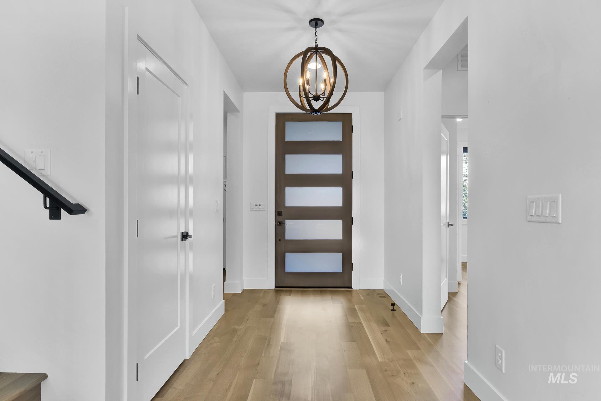 Foyer entrance with a chandelier and light wood finished floors