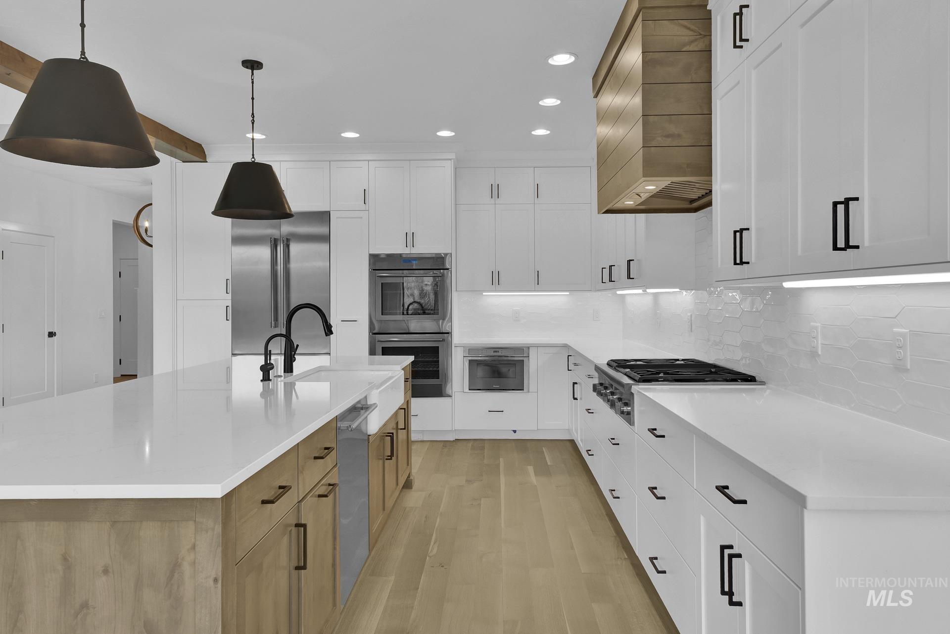 Kitchen featuring recessed lighting, light wood finished floors, appliances with stainless steel finishes, light countertops, and backsplash