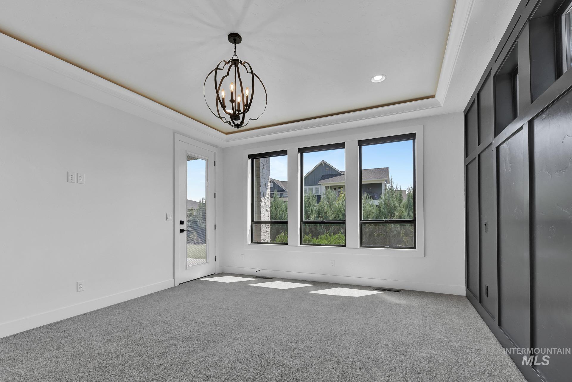 Unfurnished bedroom featuring a tray ceiling, access to outside, a chandelier, carpet, and recessed lighting