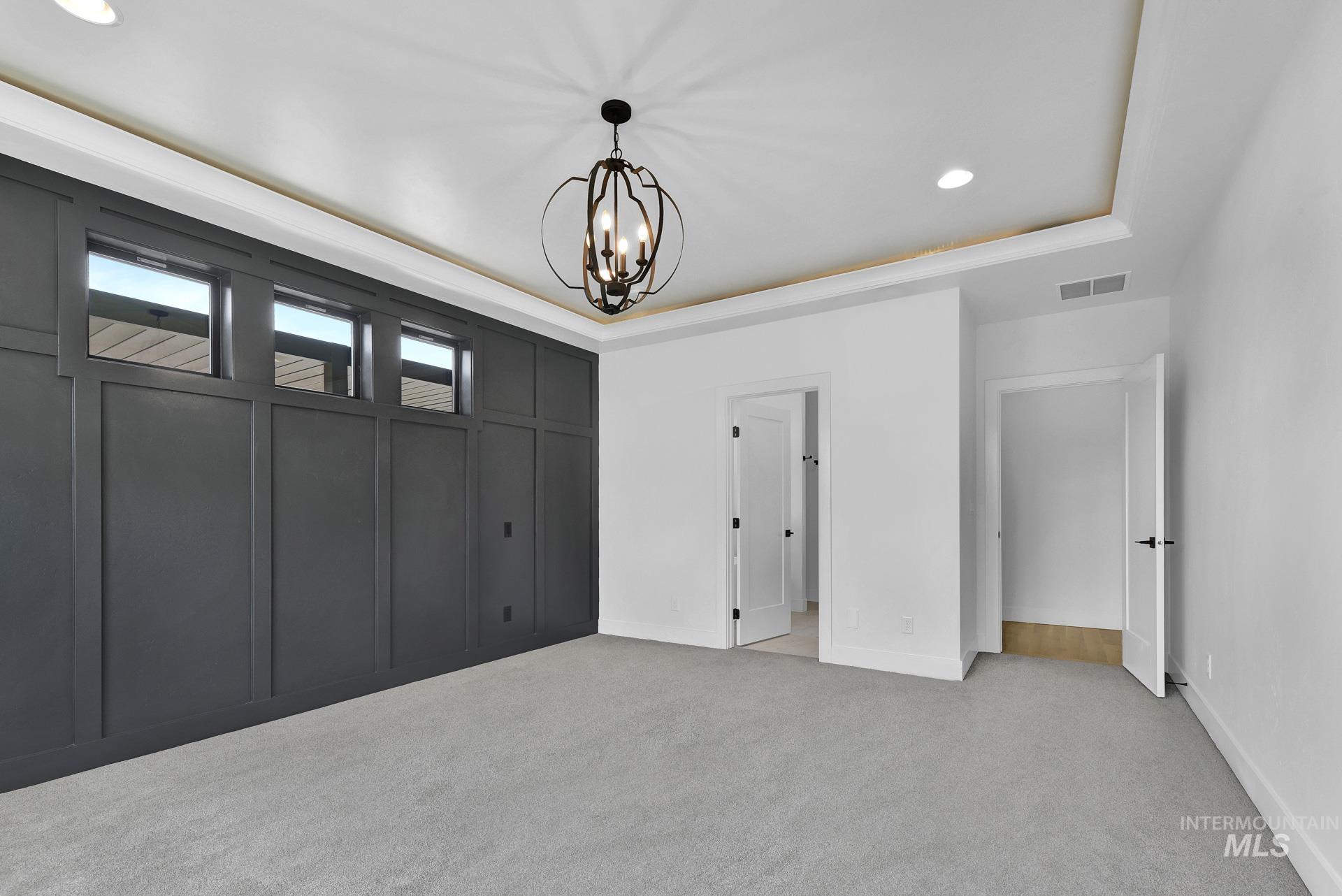 Unfurnished bedroom featuring carpet flooring, a chandelier, recessed lighting, and a raised ceiling