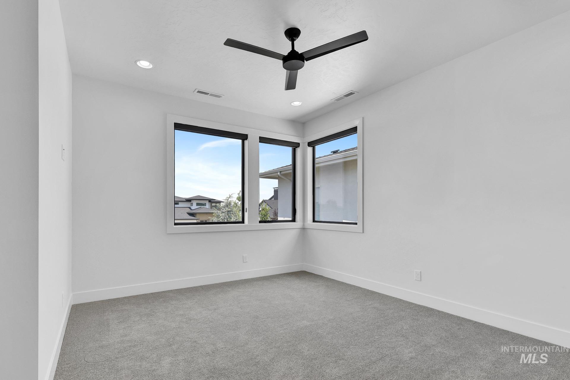 Carpeted empty room featuring a ceiling fan and recessed lighting