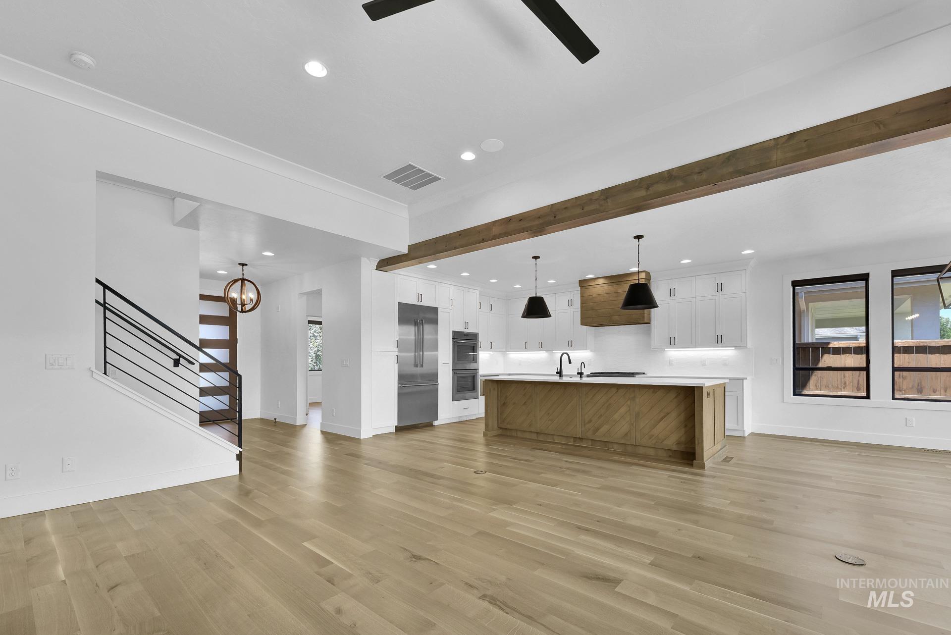 Unfurnished living room featuring ceiling fan, stairs, recessed lighting, light wood-style flooring, and ornamental molding