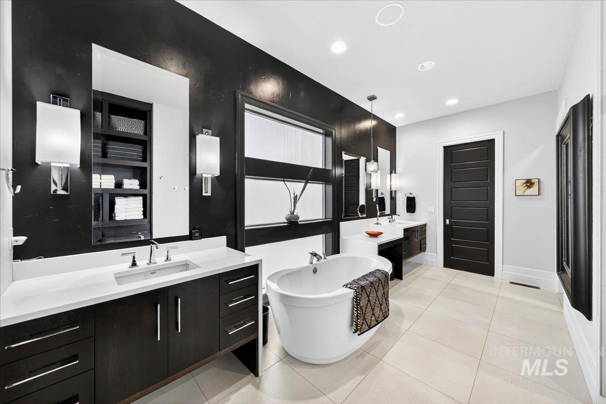 Bathroom with a freestanding bath, two vanities, light tile patterned flooring, and recessed lighting