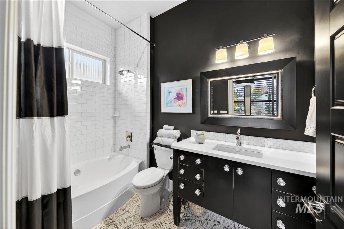 Full bath featuring shower / bathtub combination with curtain, vanity, and tile patterned floors