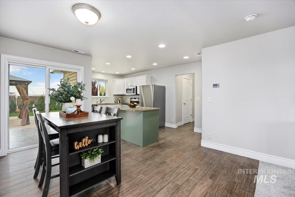 Kitchen with recessed lighting, white cabinetry, decorative backsplash, light stone countertops, and dark wood-type flooring