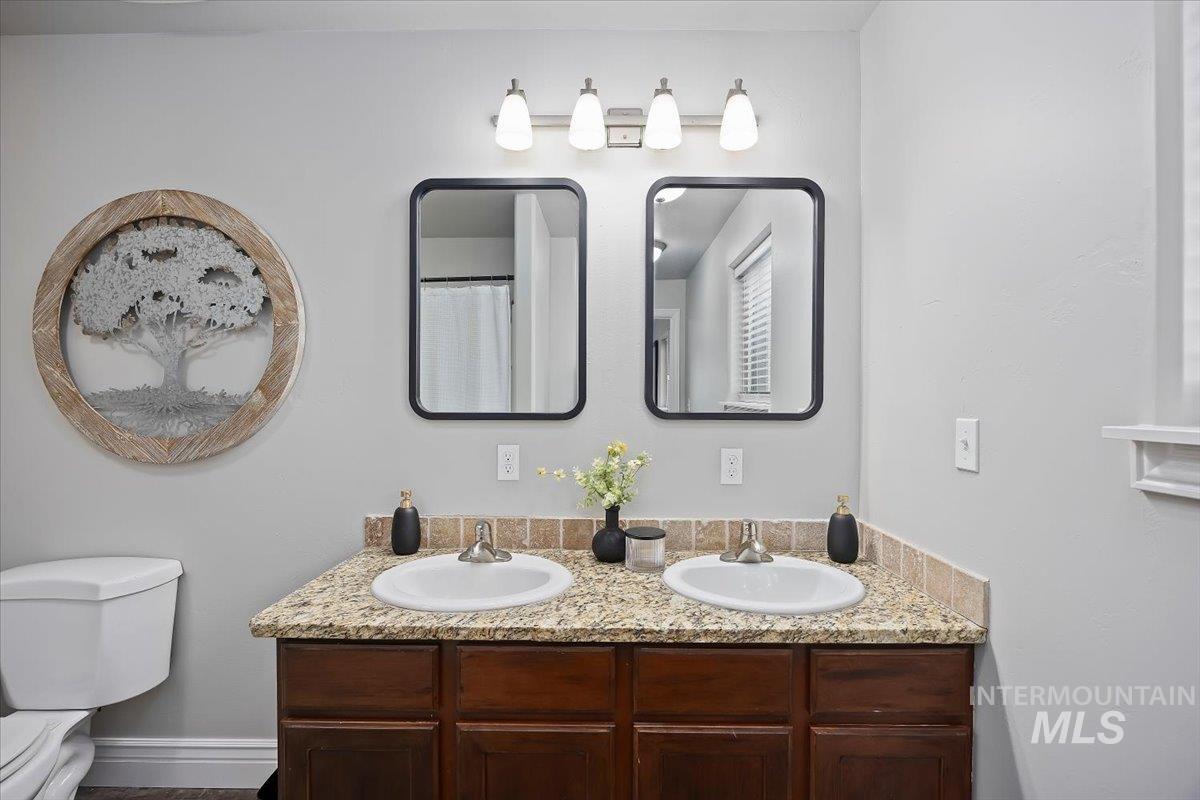 Full bath with a shower with shower curtain and double vanity