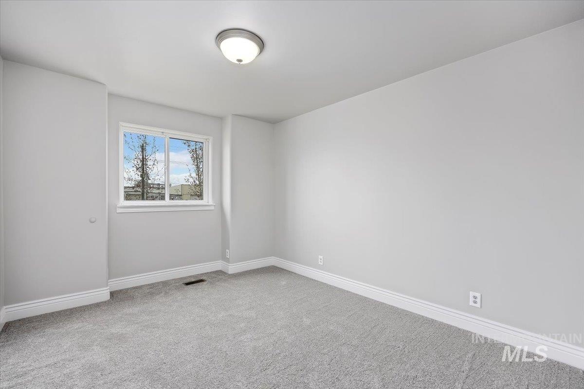 Spare room with baseboards and light colored carpet