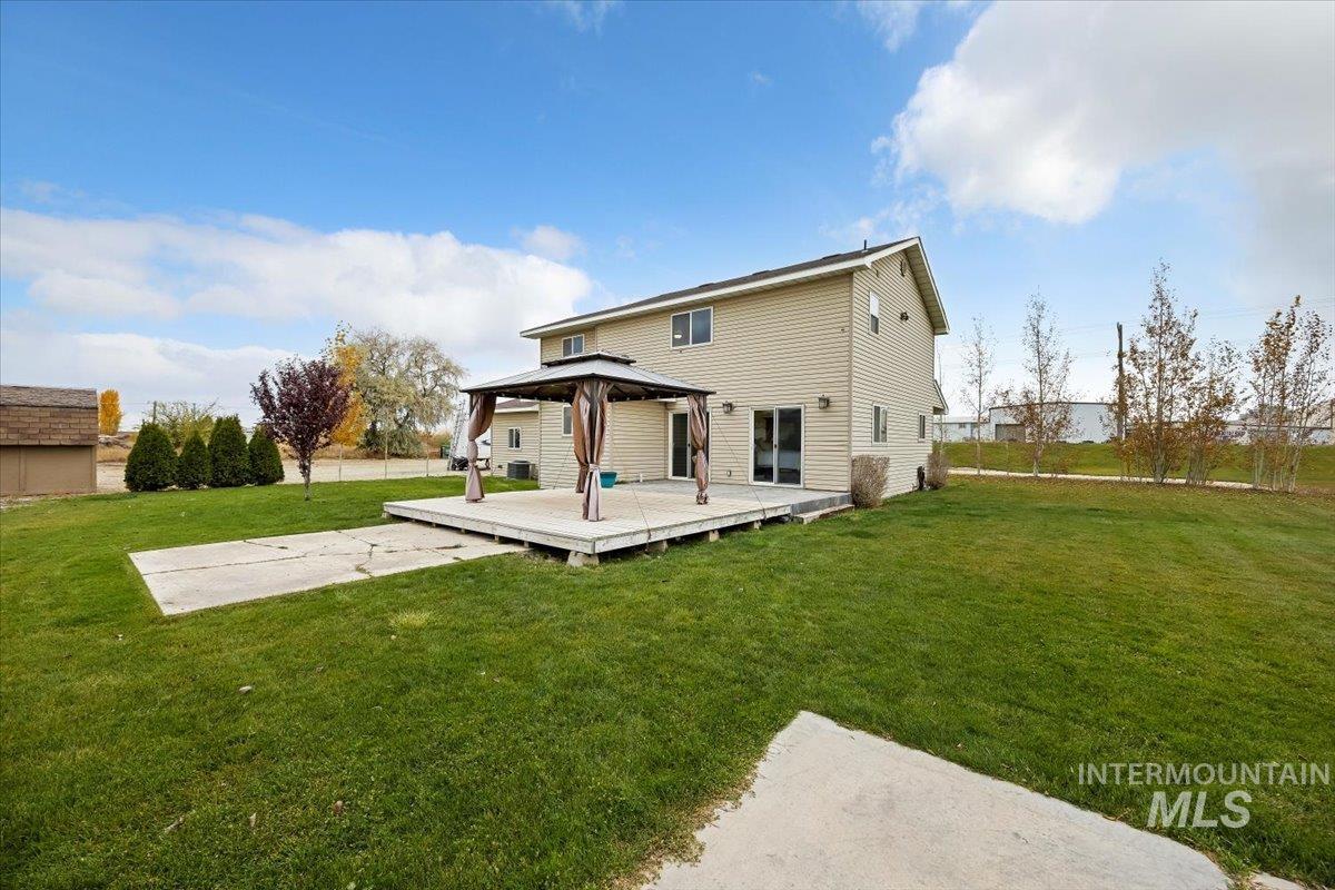 Back of property featuring a deck, a lawn, and a gazebo