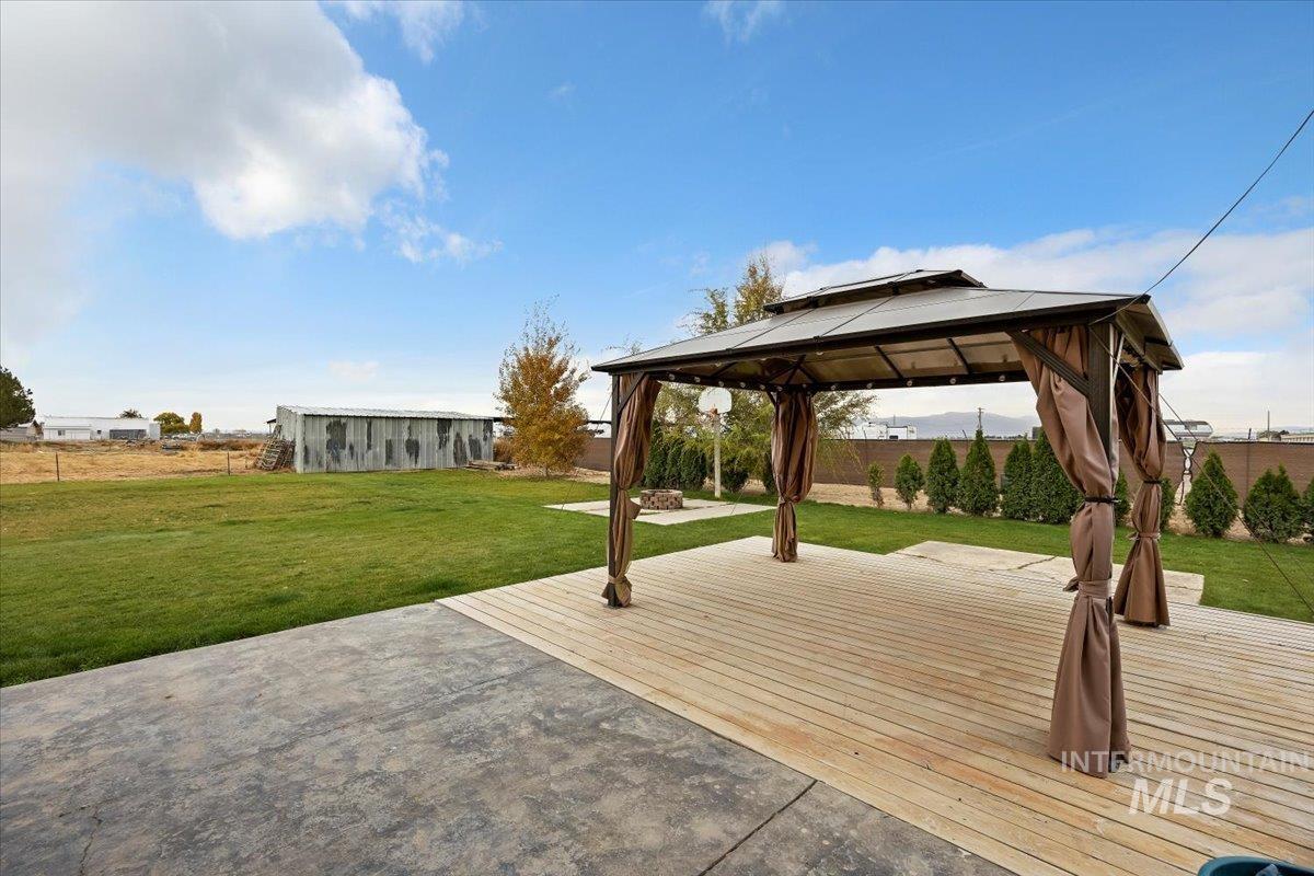 Wooden terrace featuring a gazebo, an outbuilding, and a patio area