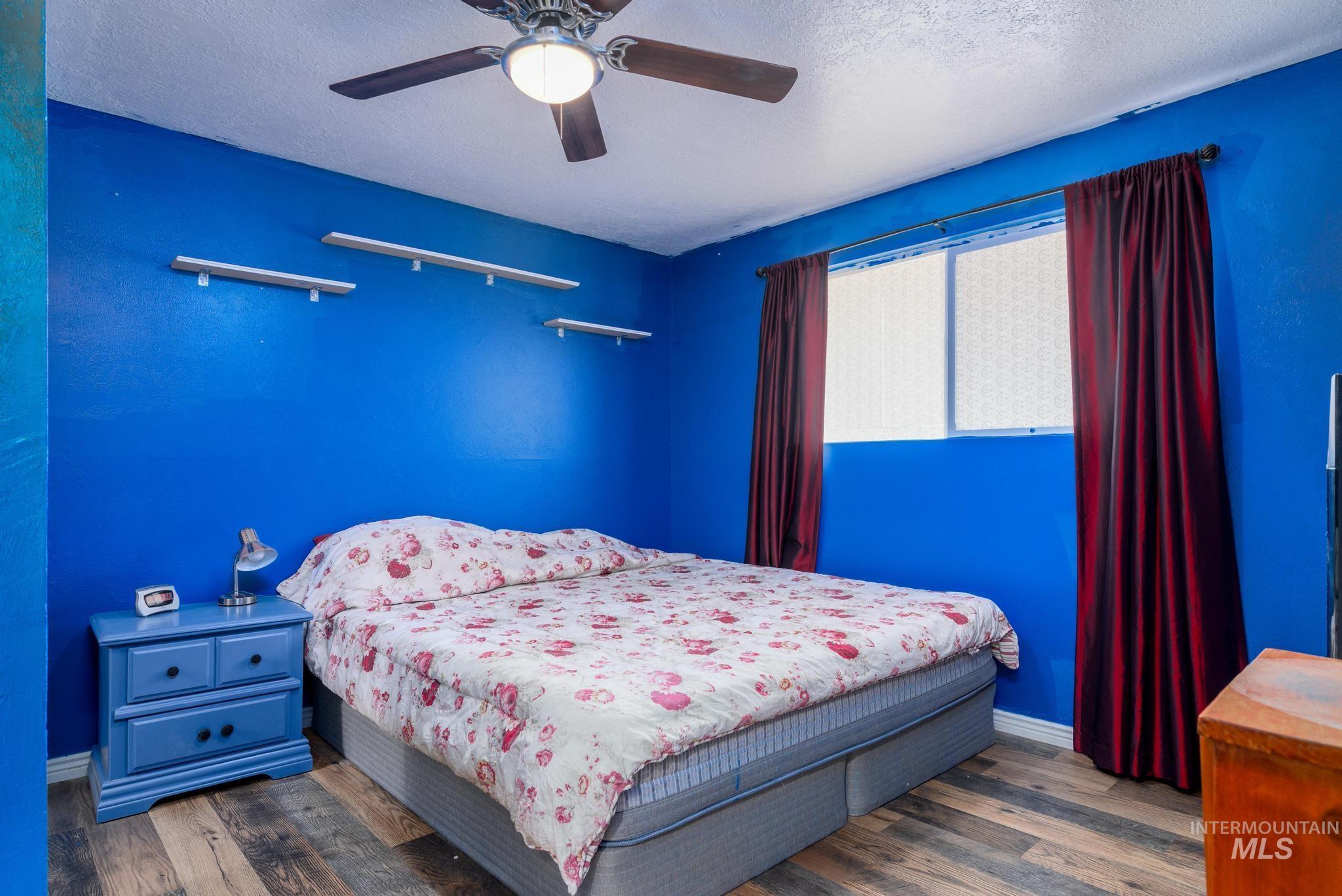 Bedroom featuring a textured ceiling, dark wood finished floors, and a ceiling fan