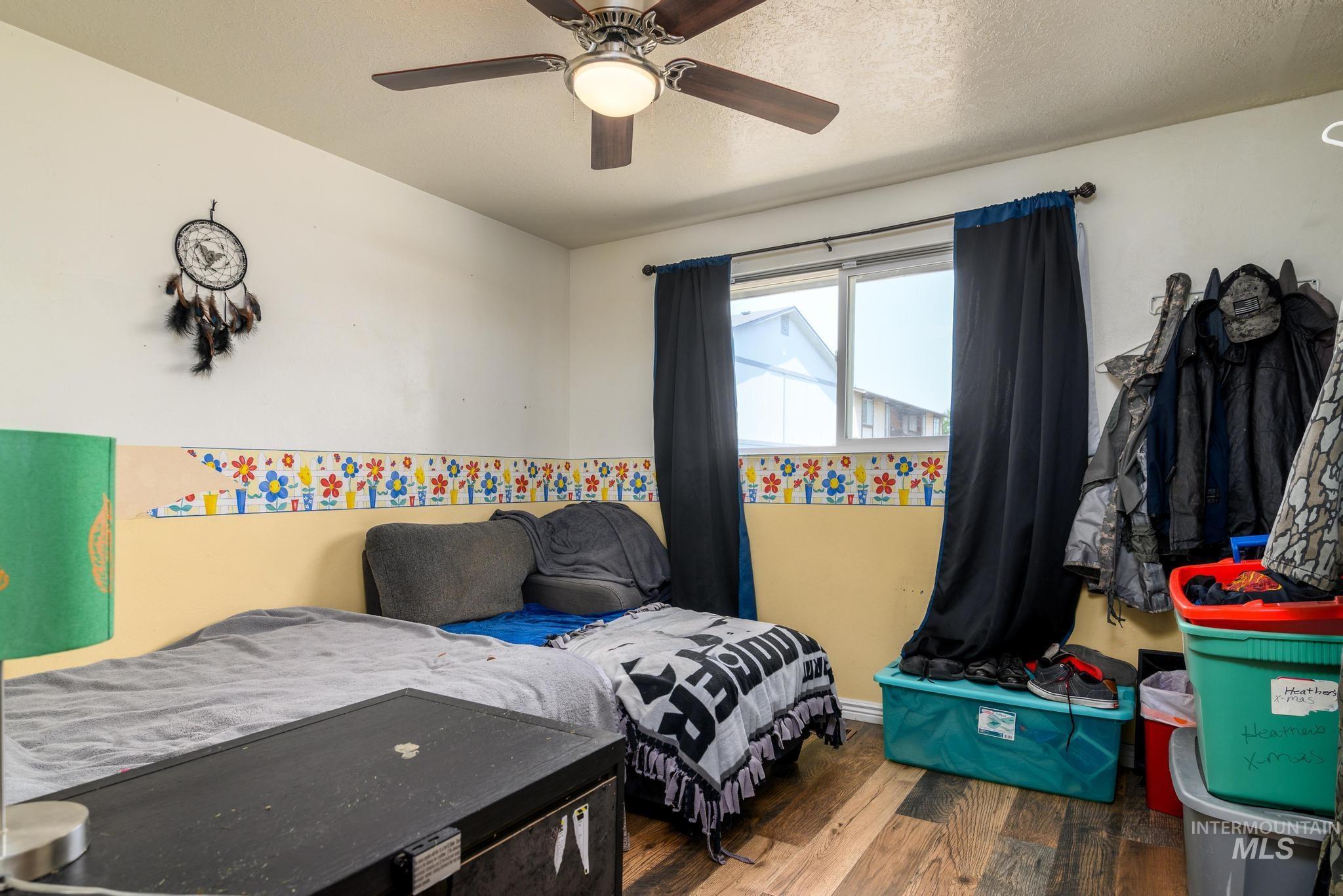 Bedroom featuring wood finished floors, a ceiling fan, and a textured ceiling