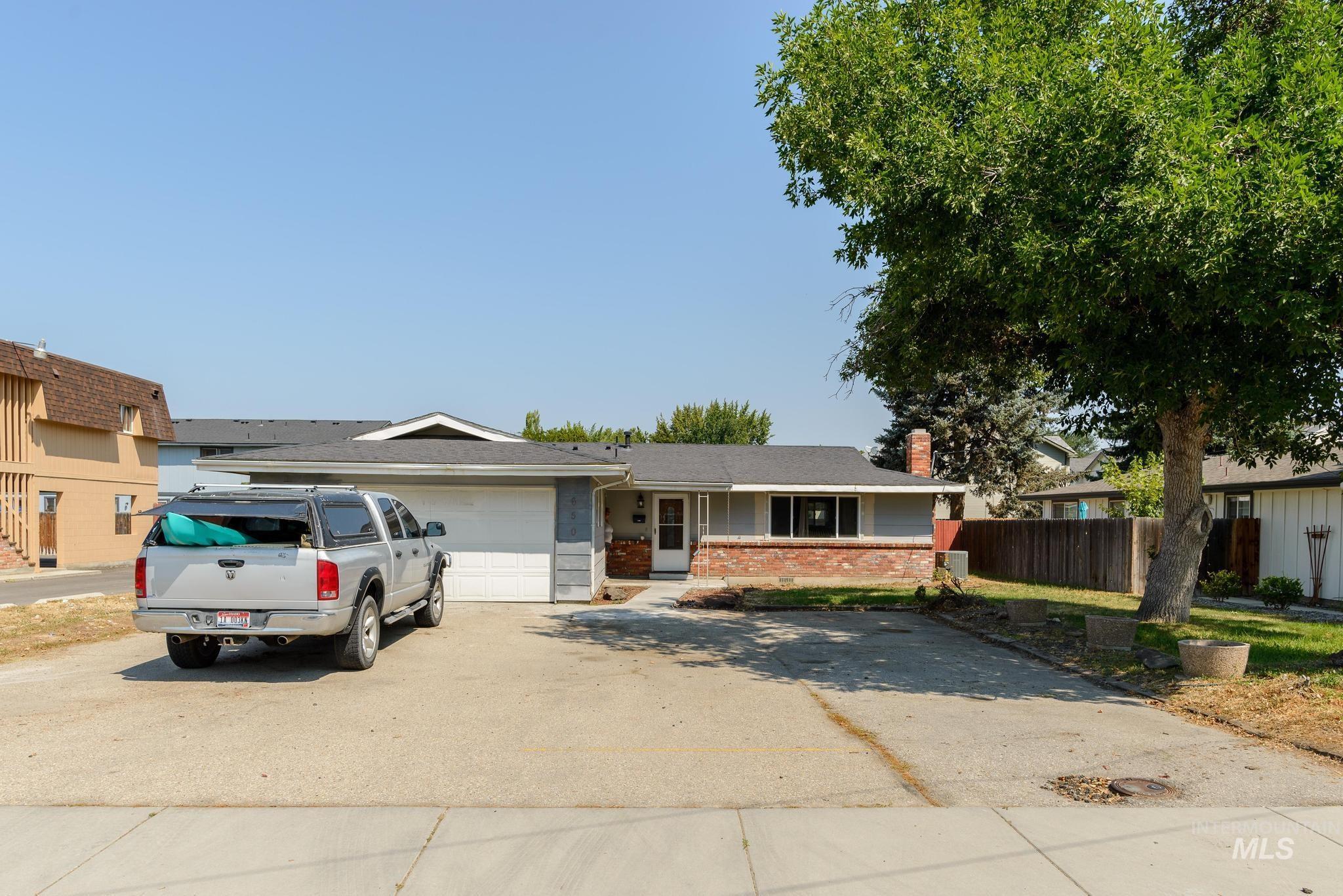 View of front of property with brick siding, concrete driveway, a chimney, and an attached garage