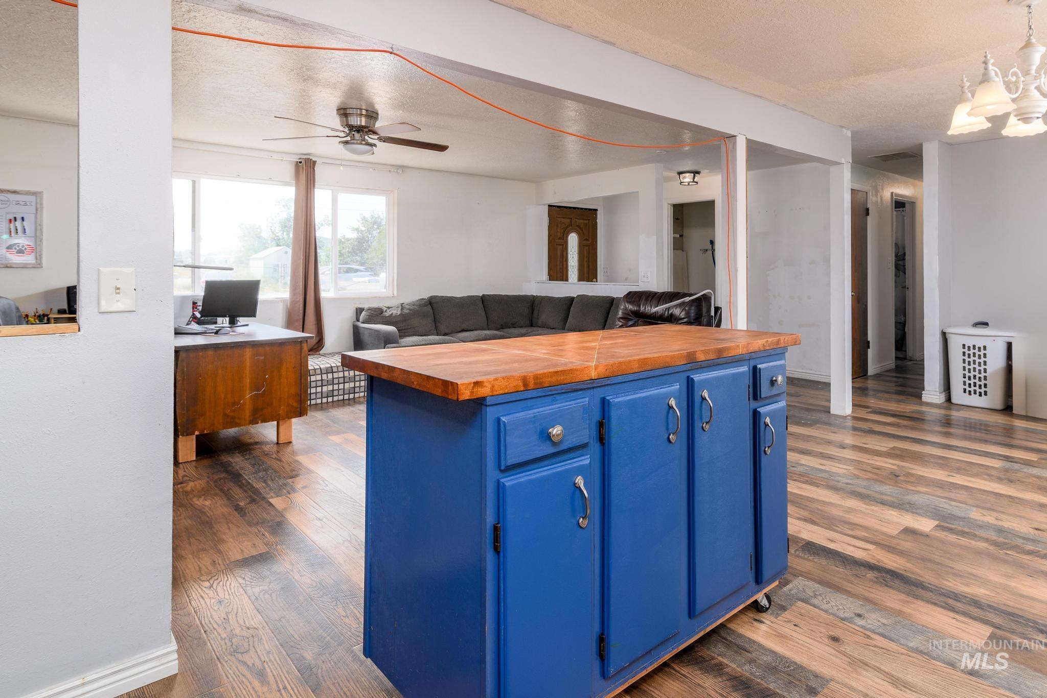 Kitchen with blue cabinetry, wood counters, open floor plan, a textured ceiling, and pendant lighting
