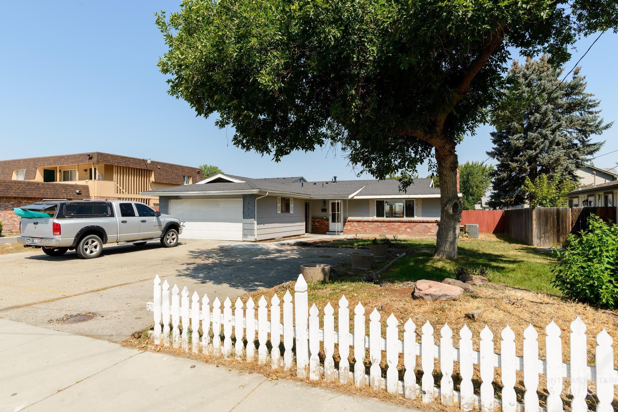Single story home featuring a fenced front yard, concrete driveway, brick siding, and an attached garage