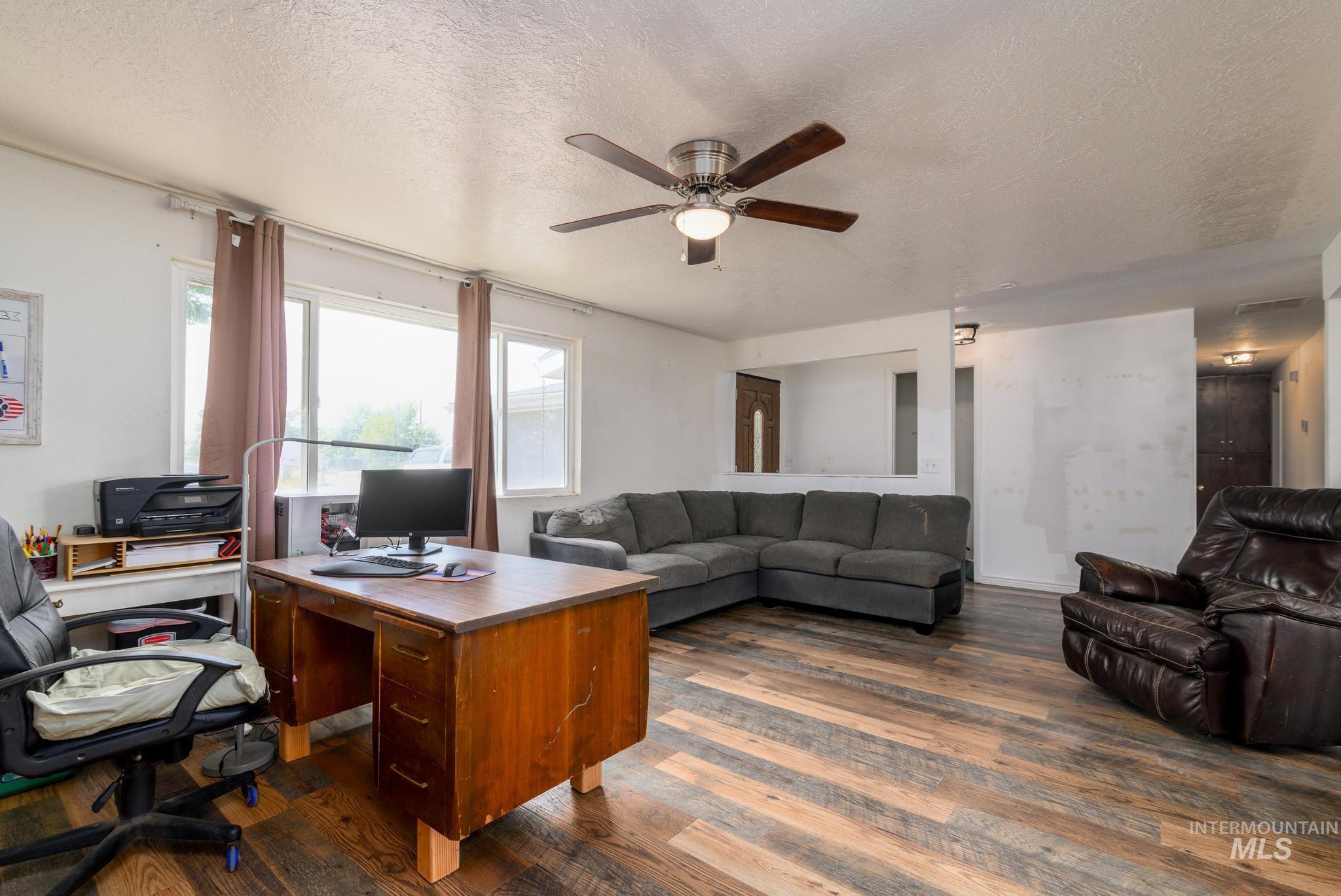 Home office with a textured ceiling, ceiling fan, and dark wood-style floors