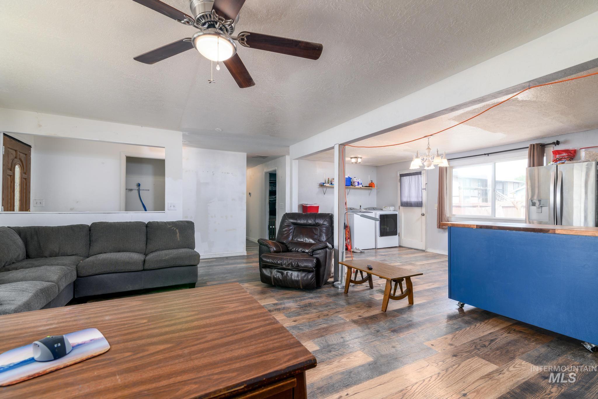 Living area with dark wood-style floors, a textured ceiling, a chandelier, and a ceiling fan