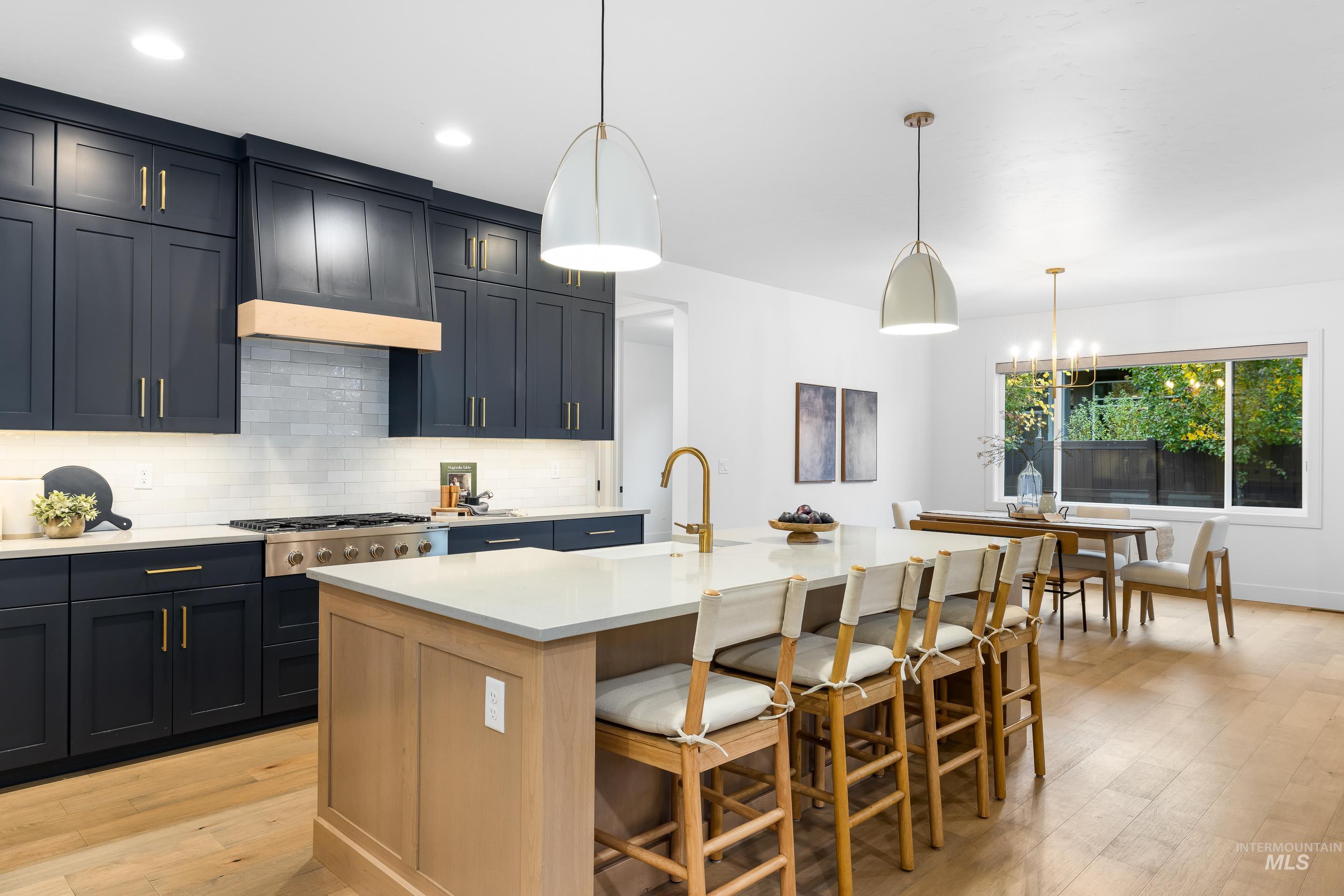 Kitchen with light wood finished floors, pendant lighting, decorative backsplash, and a breakfast bar area