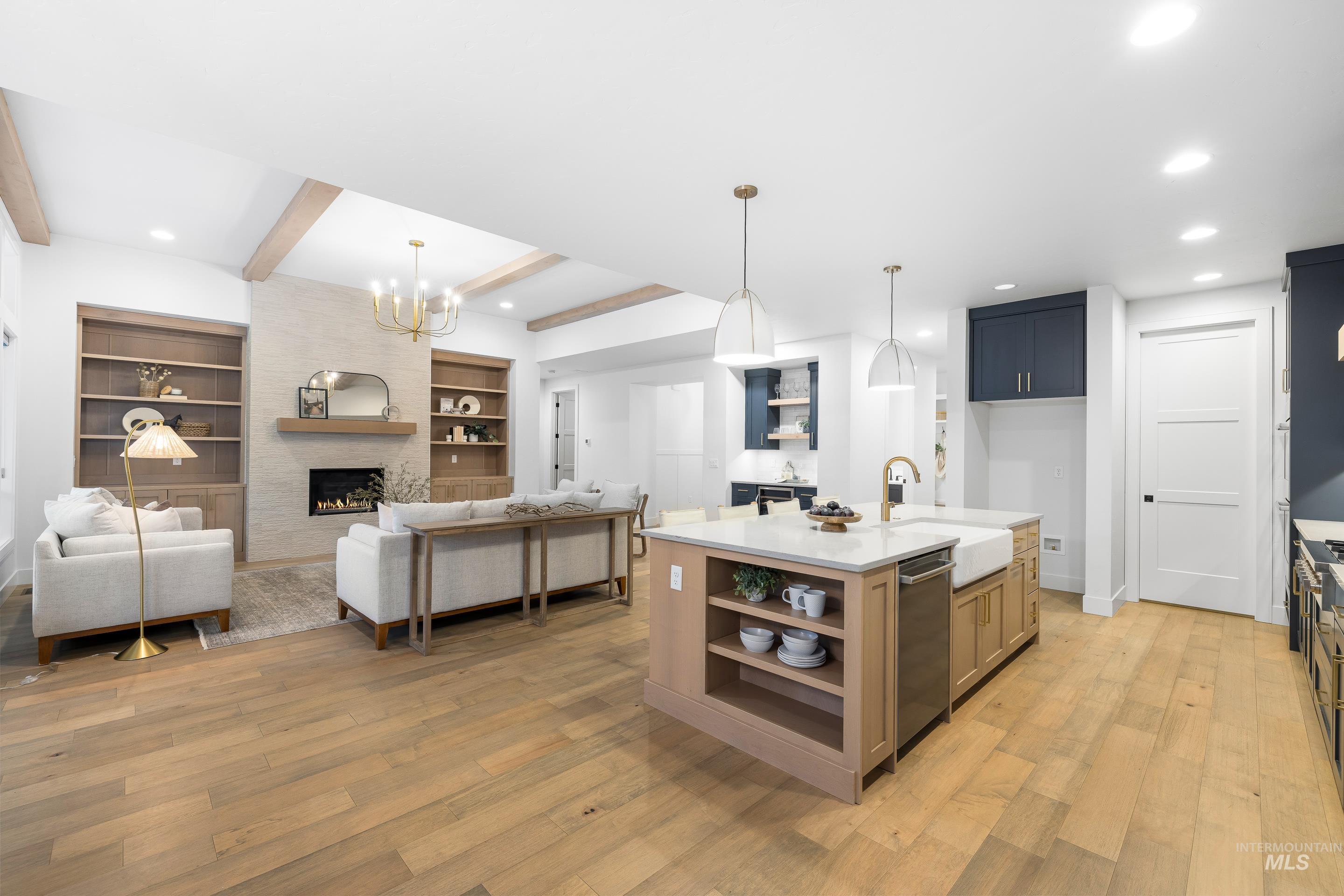 Kitchen featuring beam ceiling, recessed lighting, open floor plan, light wood finished floors, and a stone fireplace