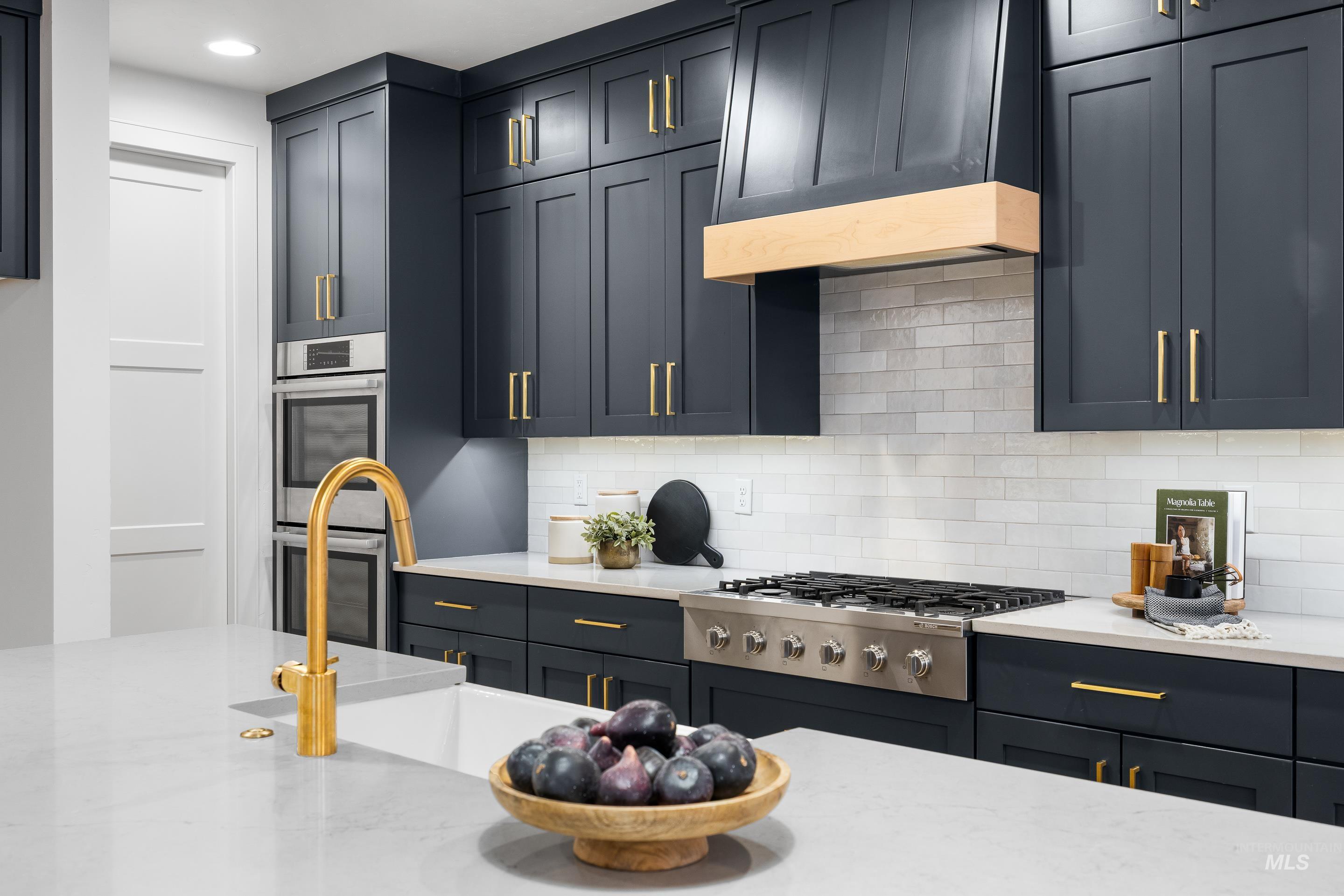 Kitchen with tasteful backsplash, premium range hood, light stone countertops, appliances with stainless steel finishes, and recessed lighting