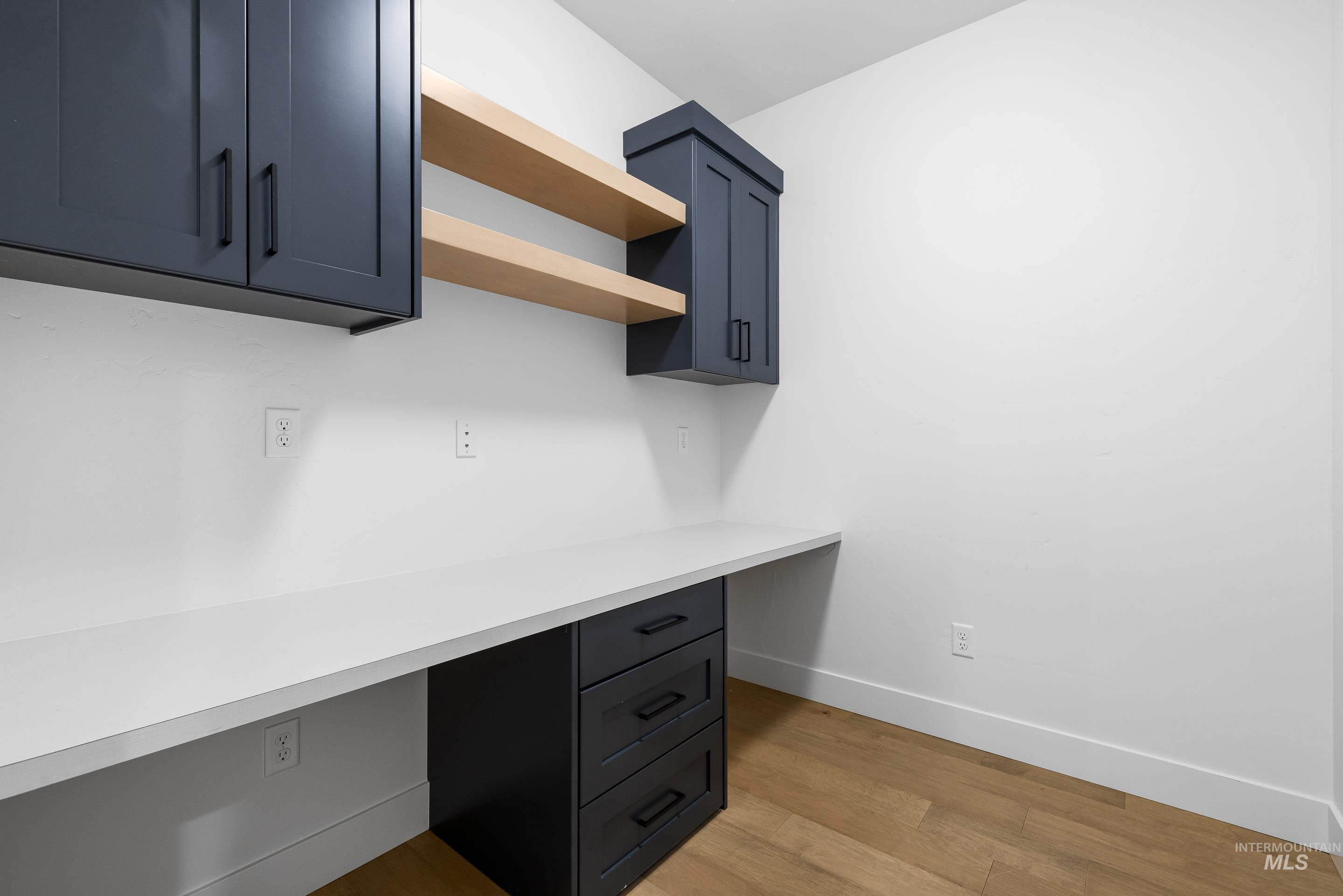 Unfurnished office with light wood-type flooring and built in desk