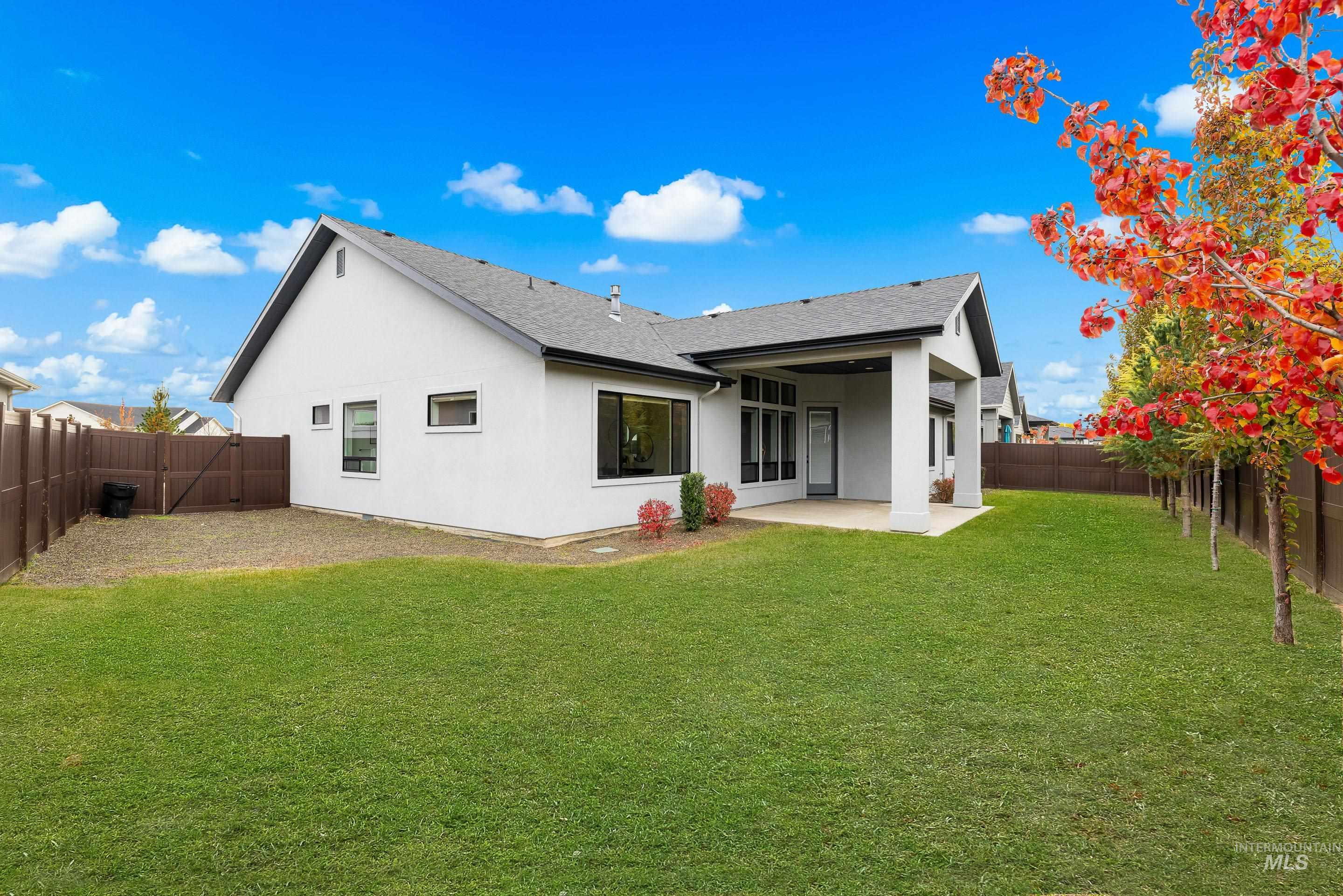 Rear view of property featuring roof with shingles, a fenced backyard, stucco siding, and a patio
