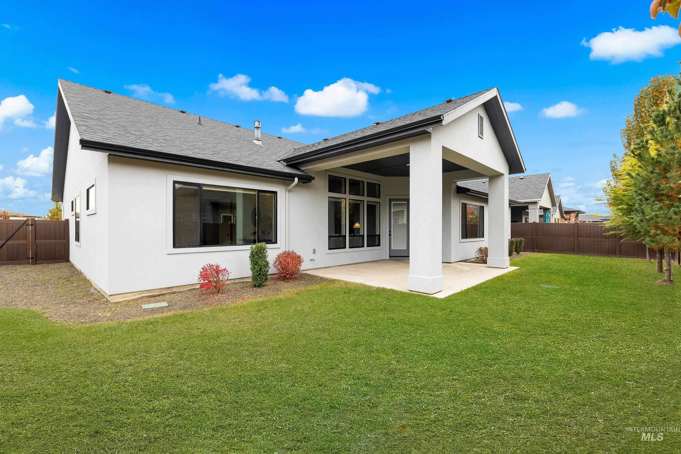 Back of property with a shingled roof, a fenced backyard, stucco siding, and a patio