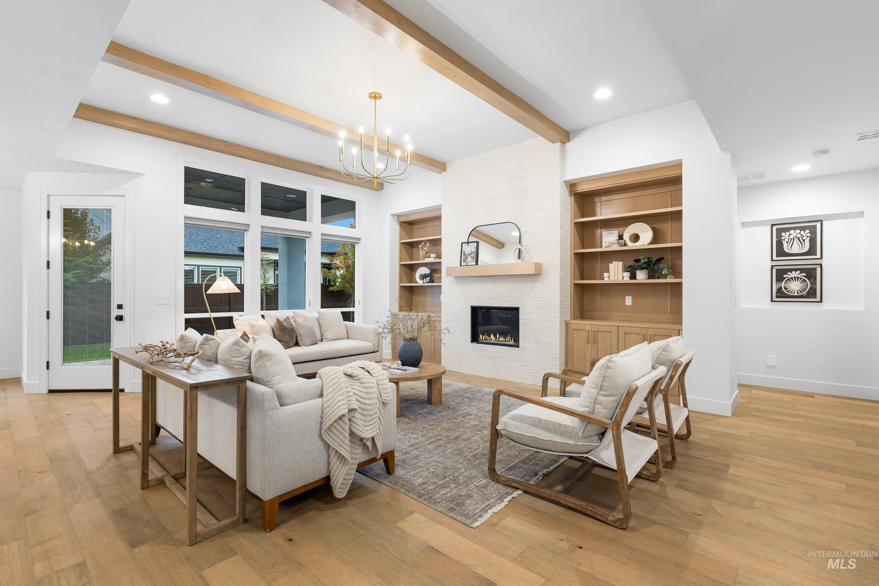 Living area featuring recessed lighting, beam ceiling, light wood-style flooring, a large fireplace, and a chandelier
