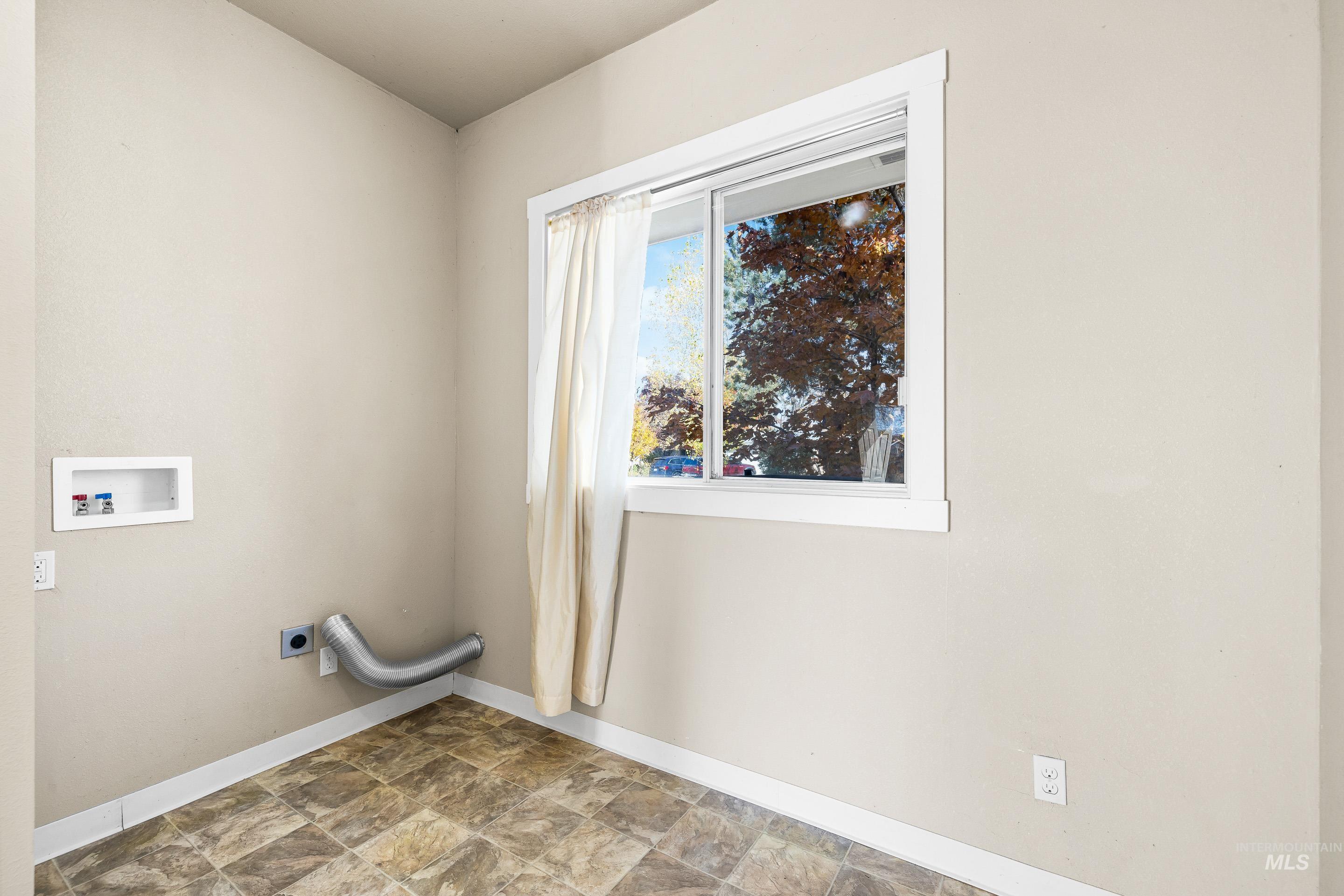 Laundry area featuring electric dryer hookup, washer hookup, and stone finish flooring