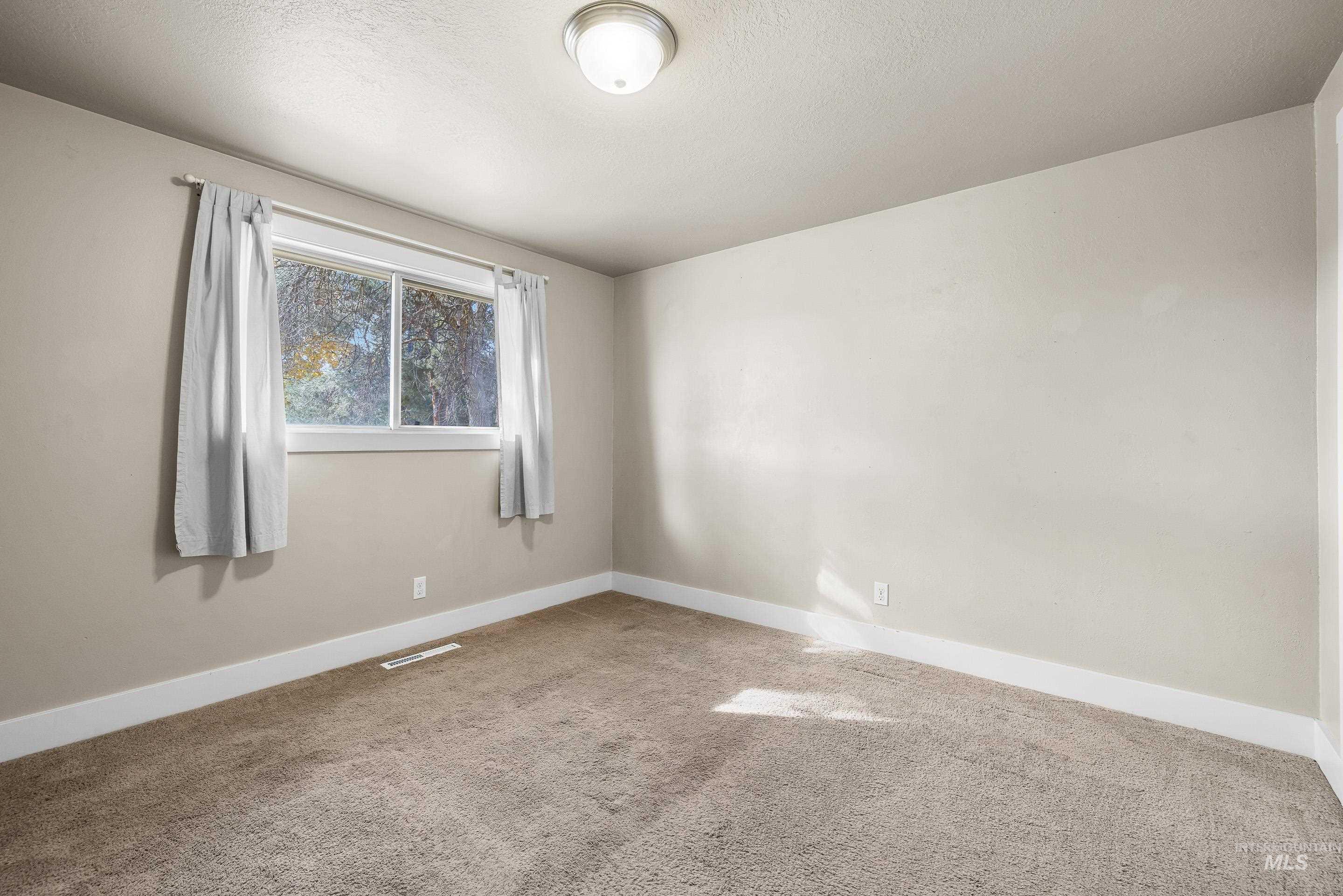 Empty room featuring light carpet and a textured ceiling