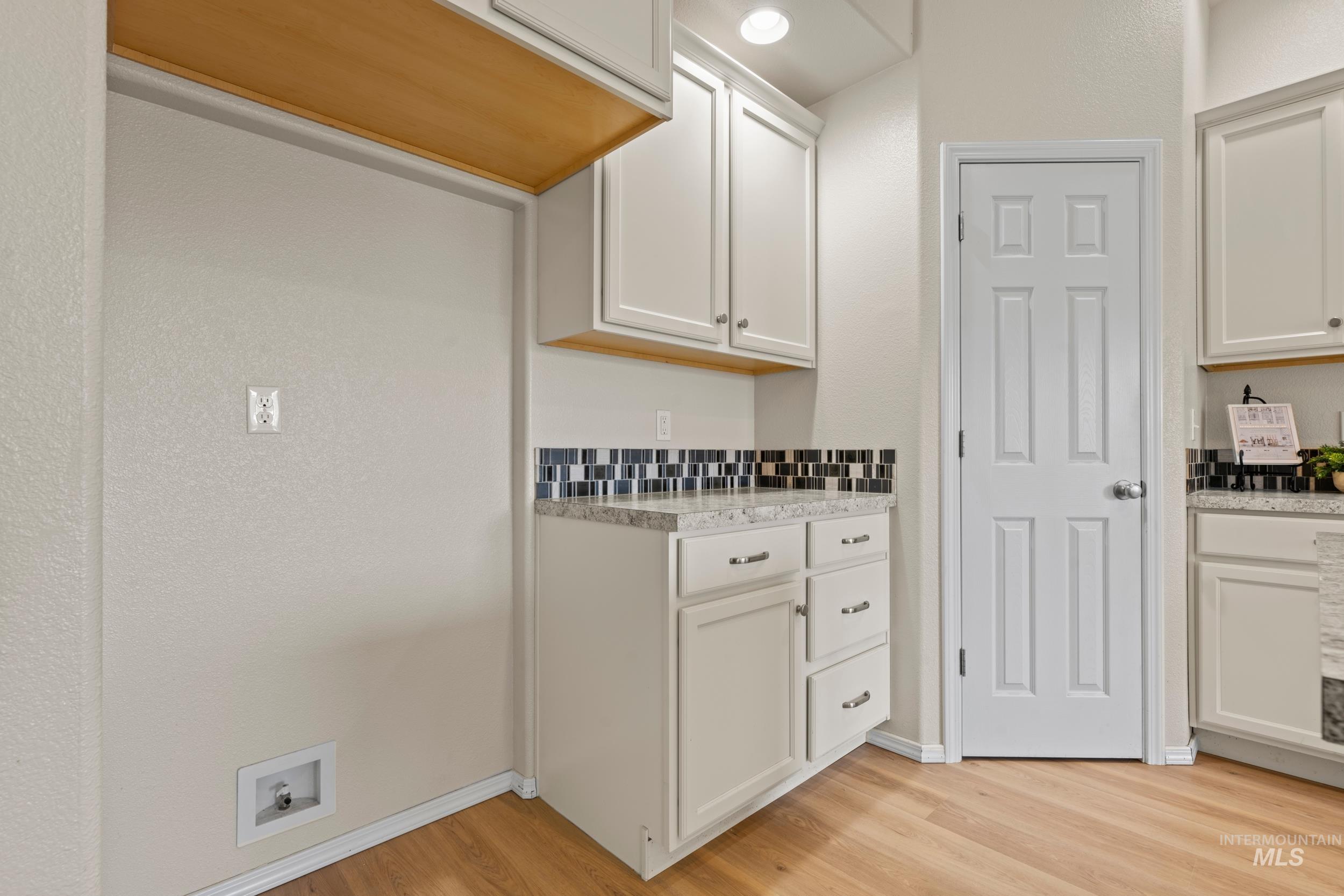 Kitchen featuring white cabinetry, light wood-style flooring, and light stone countertops