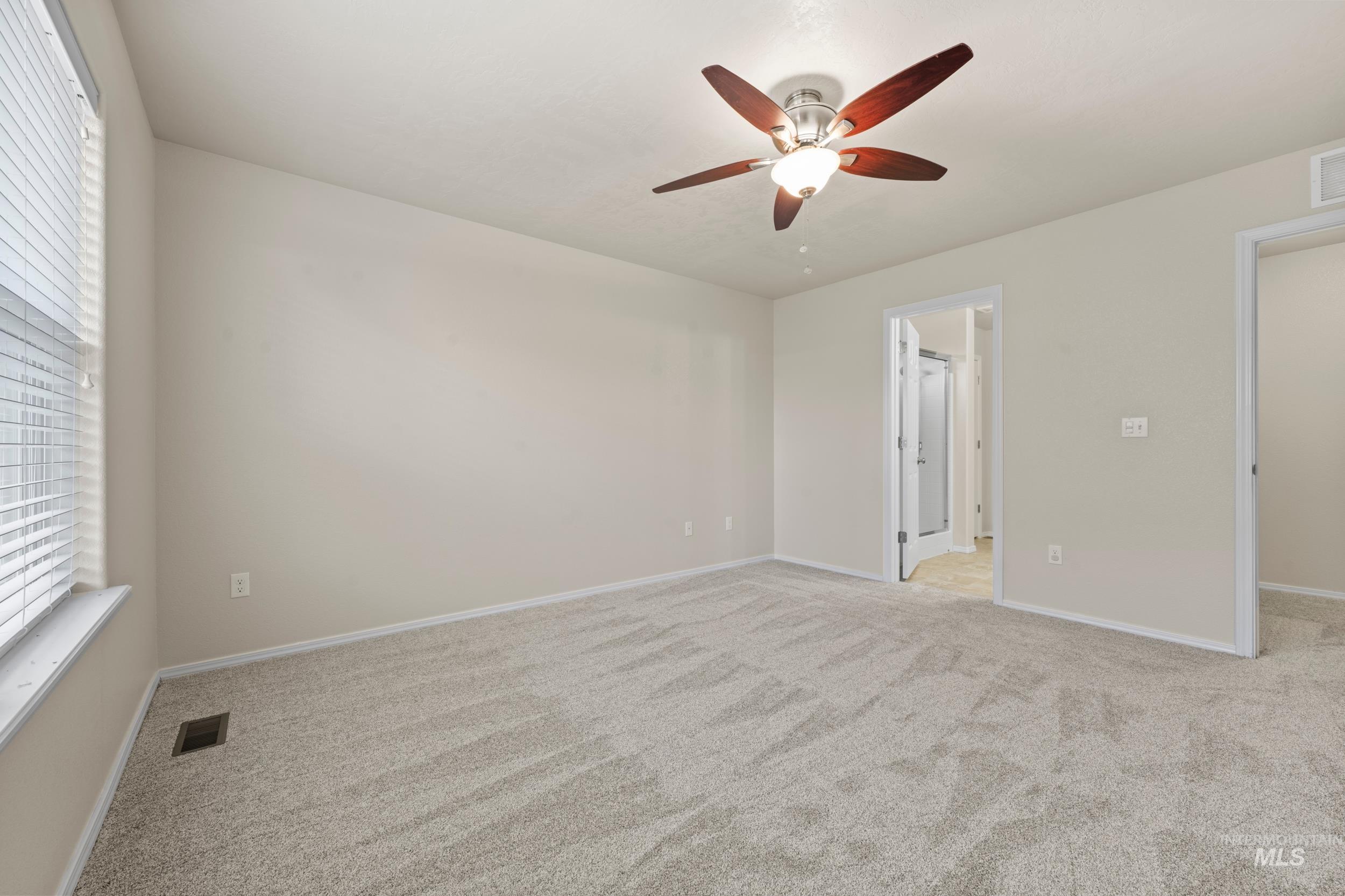 Unfurnished bedroom with light colored carpet and a ceiling fan