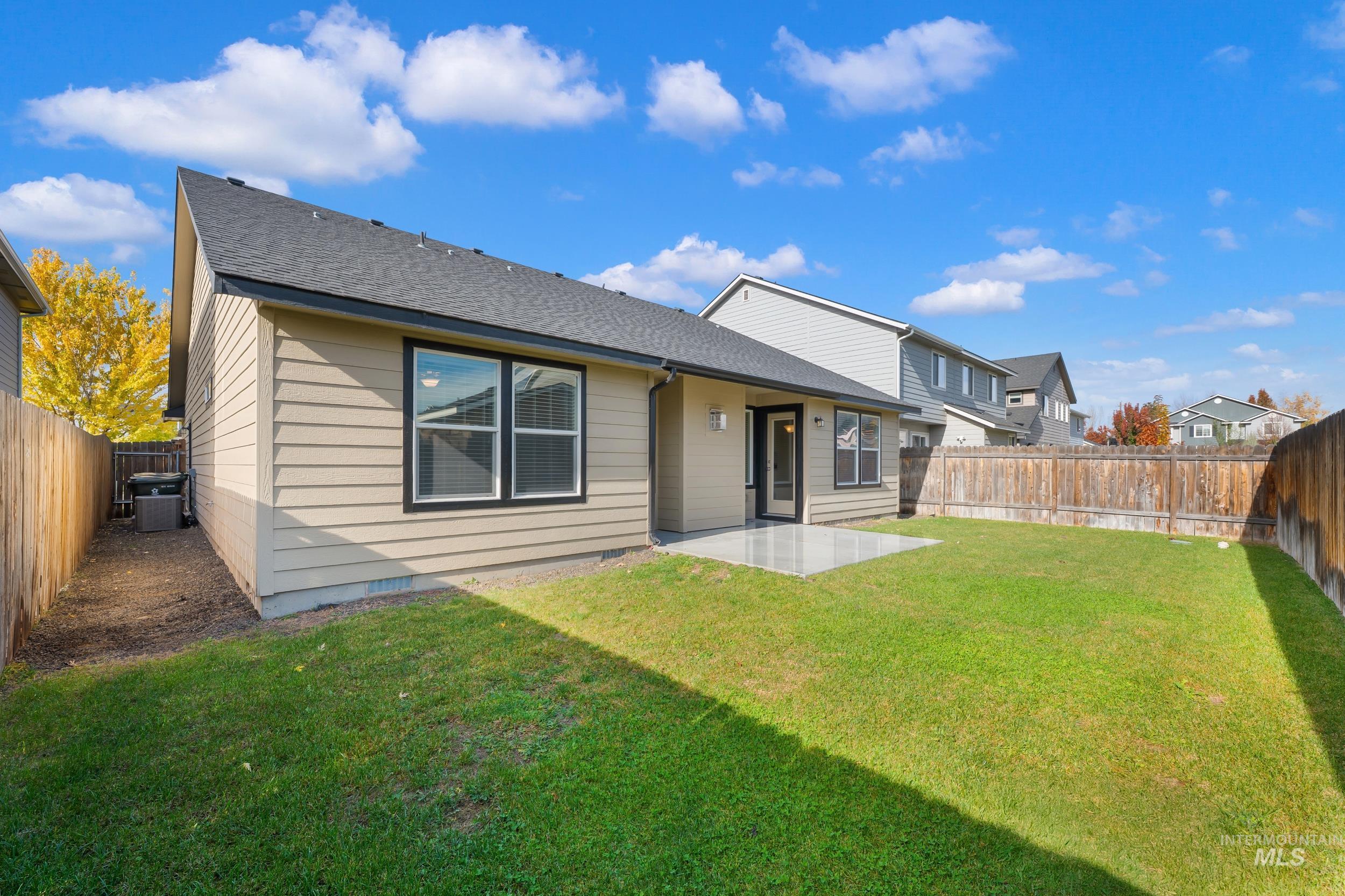 Rear view of property featuring a patio area, a fenced backyard, and a shingled roof