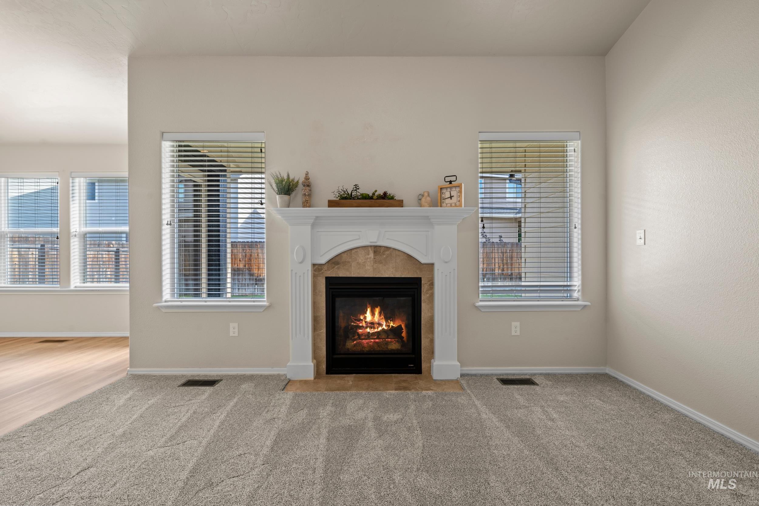 Unfurnished living room with carpet, plenty of natural light, and a tile fireplace