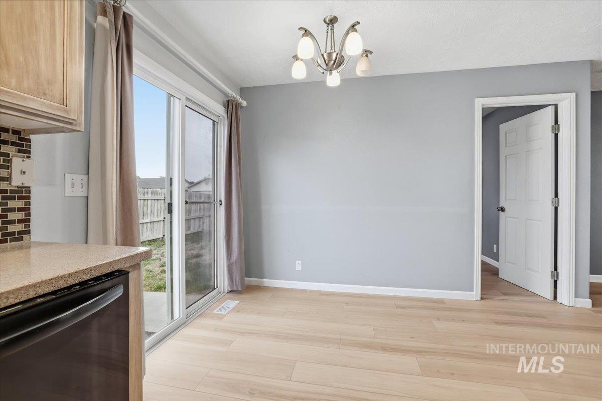 Unfurnished dining area featuring light wood-type flooring and a chandelier