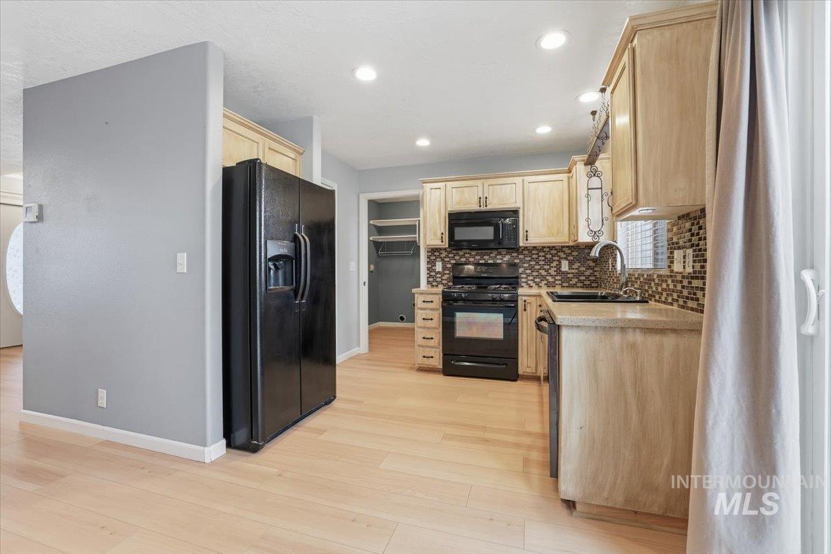 Kitchen with light brown cabinetry, black appliances, decorative backsplash, and recessed lighting