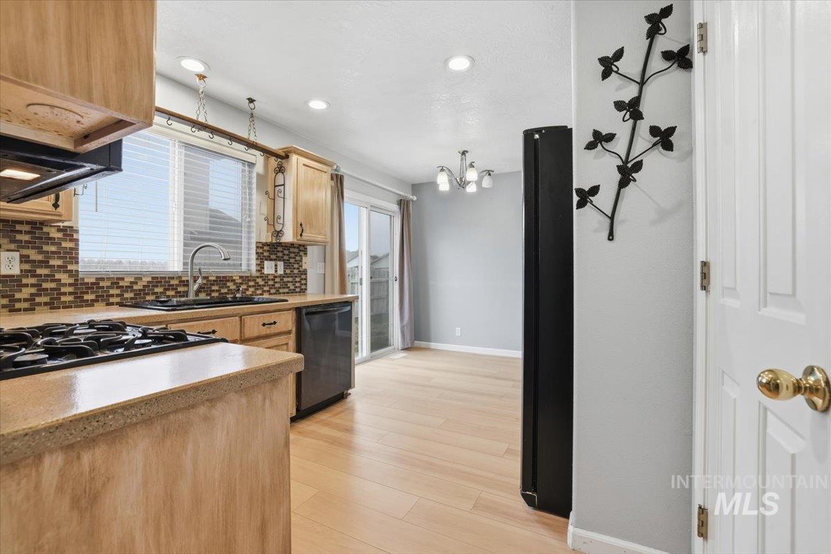 Kitchen with backsplash, light countertops, black appliances, light wood-type flooring, and recessed lighting