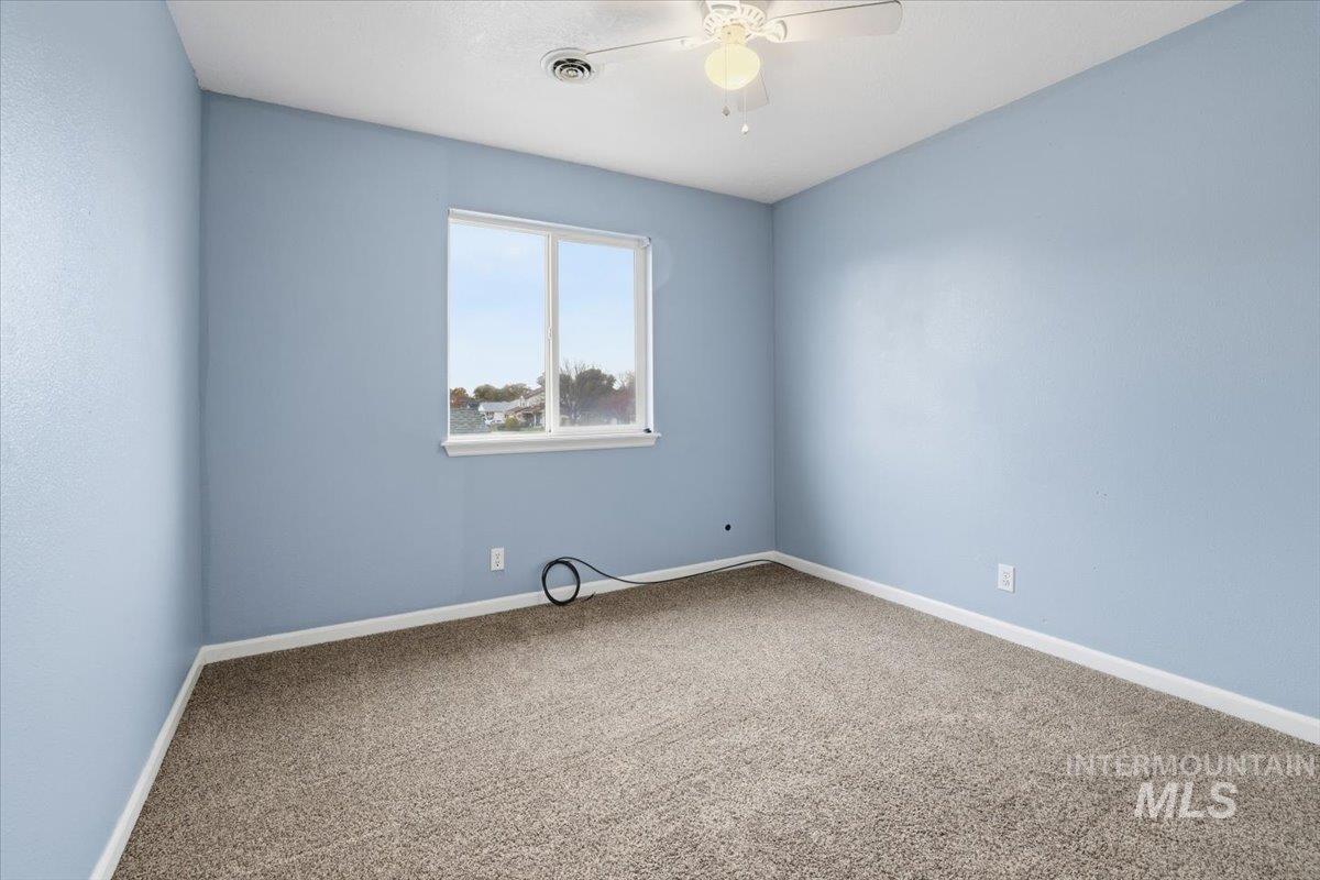 Empty room featuring carpet flooring and a ceiling fan