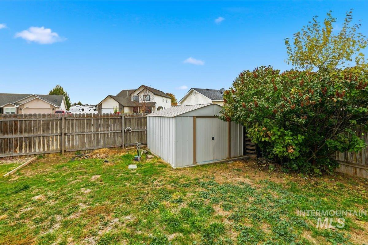 Fenced backyard featuring a storage unit and a residential view