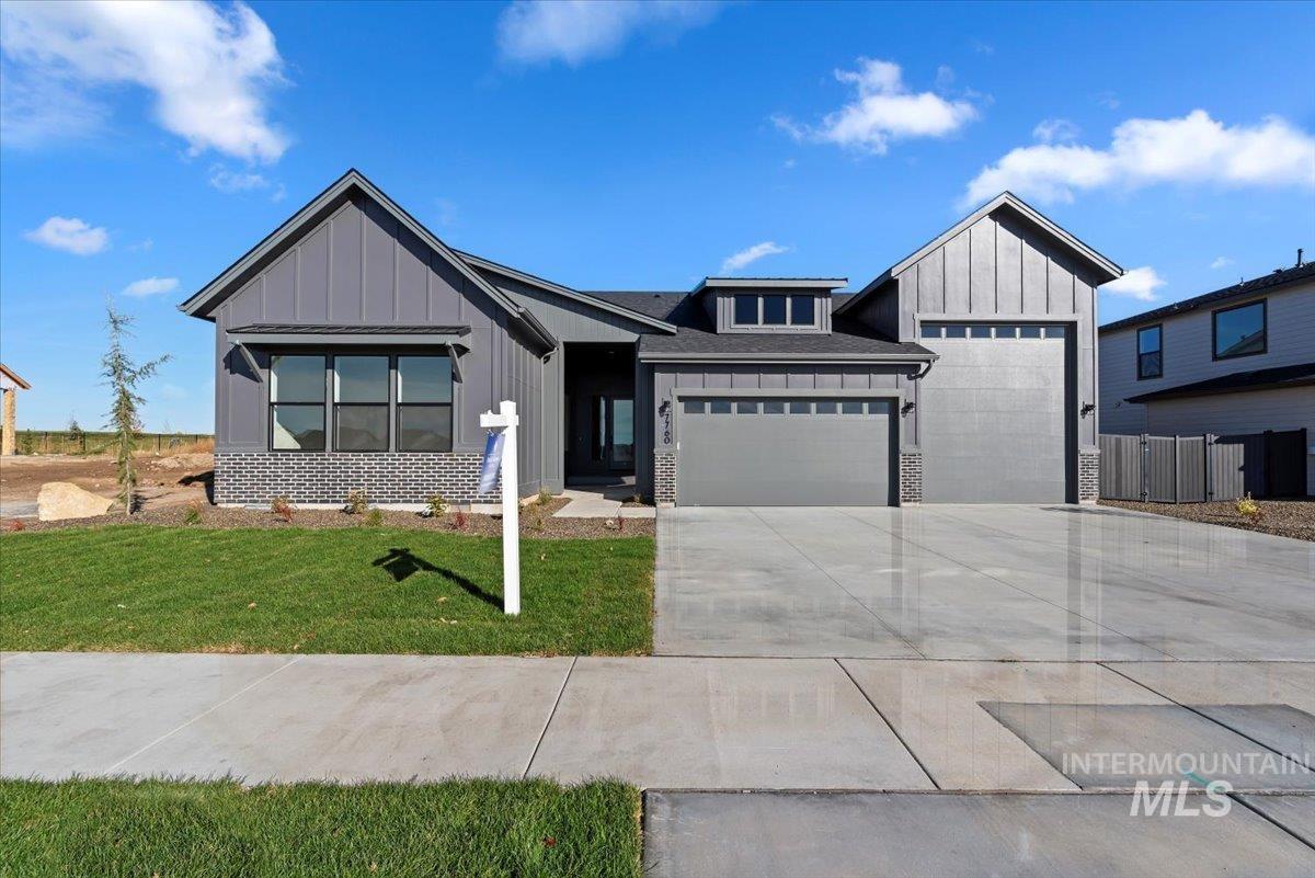 Modern farmhouse style home featuring board and batten siding, a garage, concrete driveway, and a front lawn