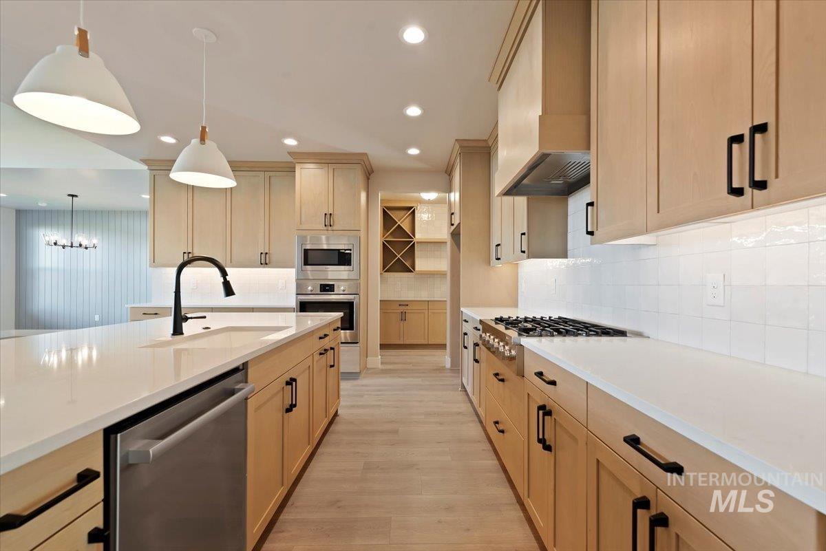 Kitchen featuring stainless steel appliances, decorative light fixtures, light brown cabinets, light stone countertops, and recessed lighting