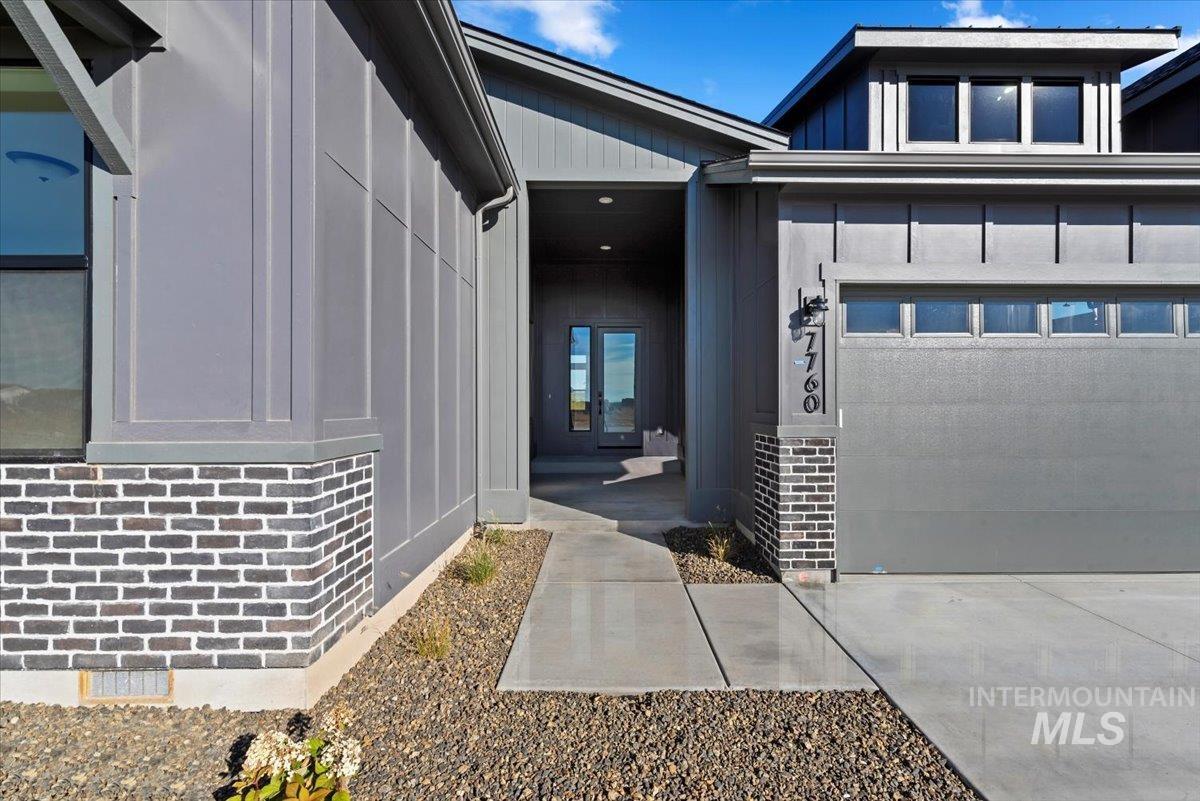 Entrance to property with brick siding, board and batten siding, and a garage