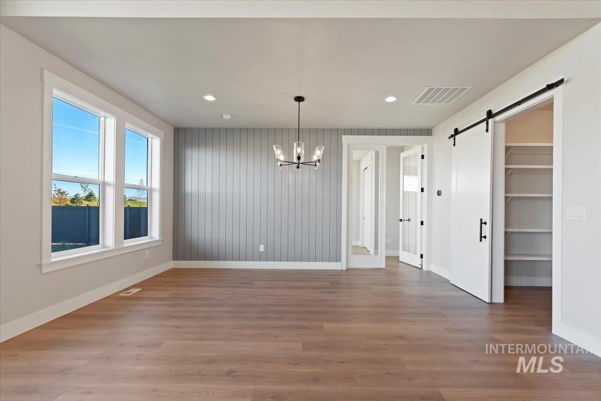 Unfurnished dining area with a barn door, a chandelier, recessed lighting, and light wood-style floors
