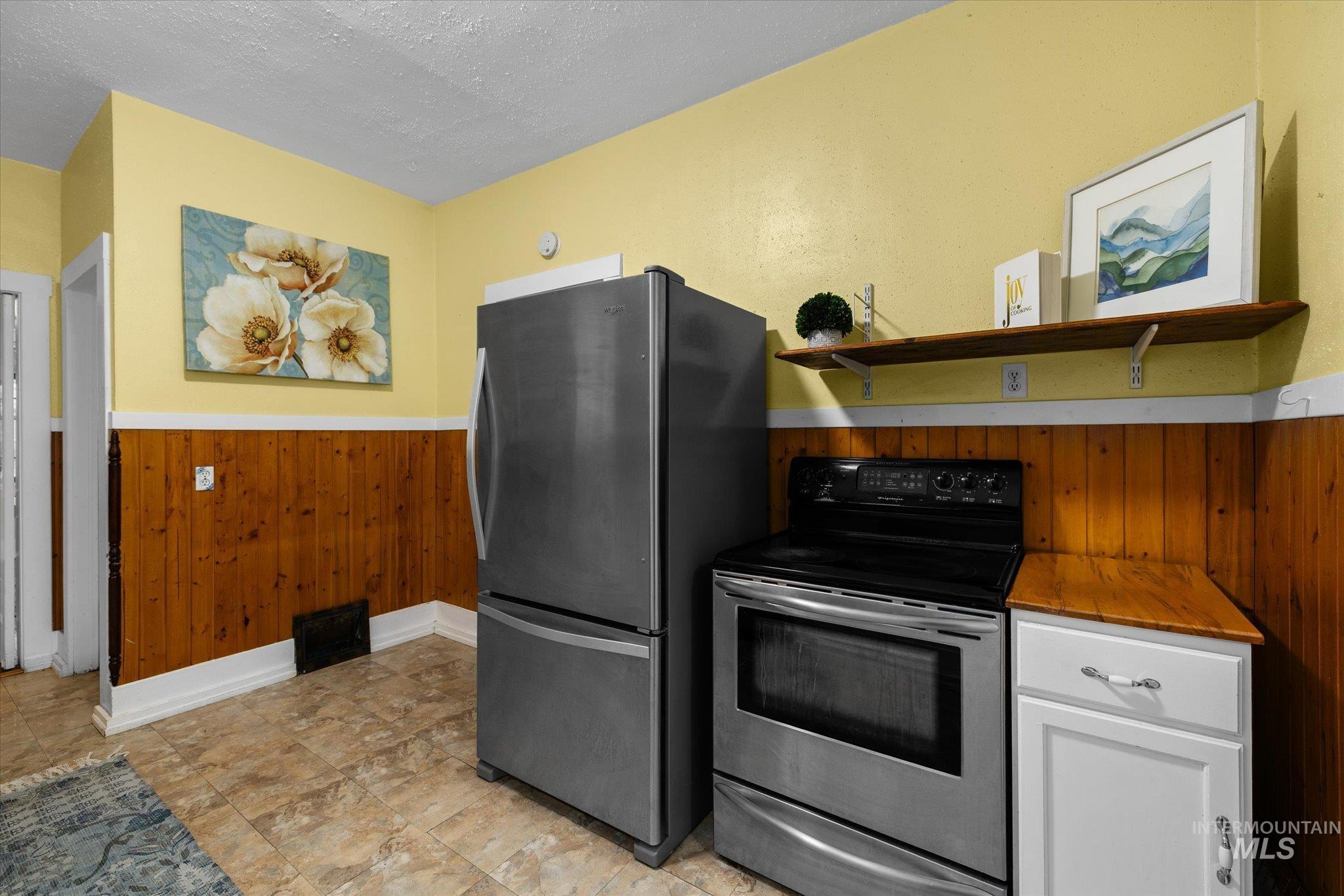 Kitchen with open shelves, wooden walls, appliances with stainless steel finishes, a wainscoted wall, and white cabinets