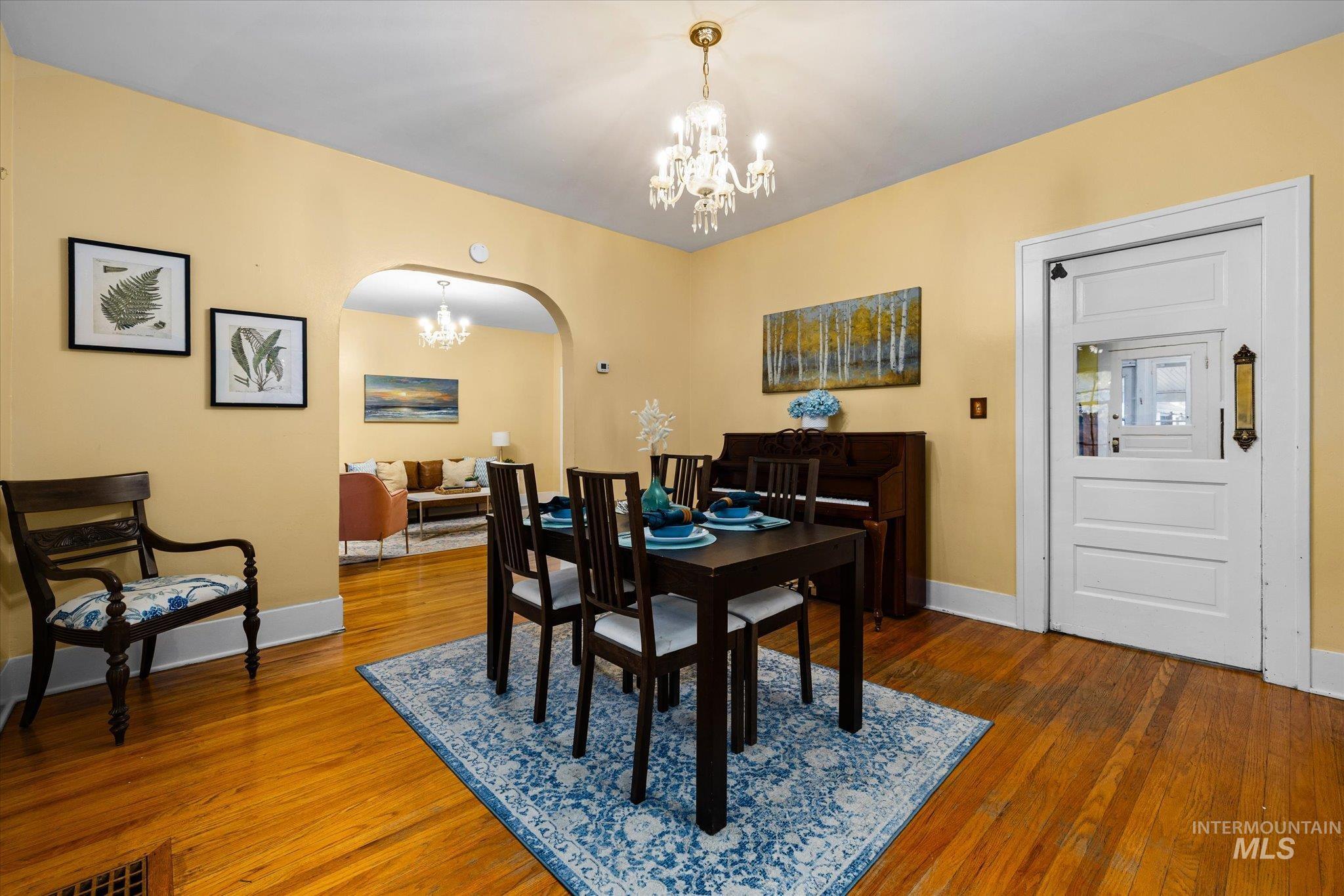 Dining room with arched walkways, a chandelier, and dark wood-style flooring