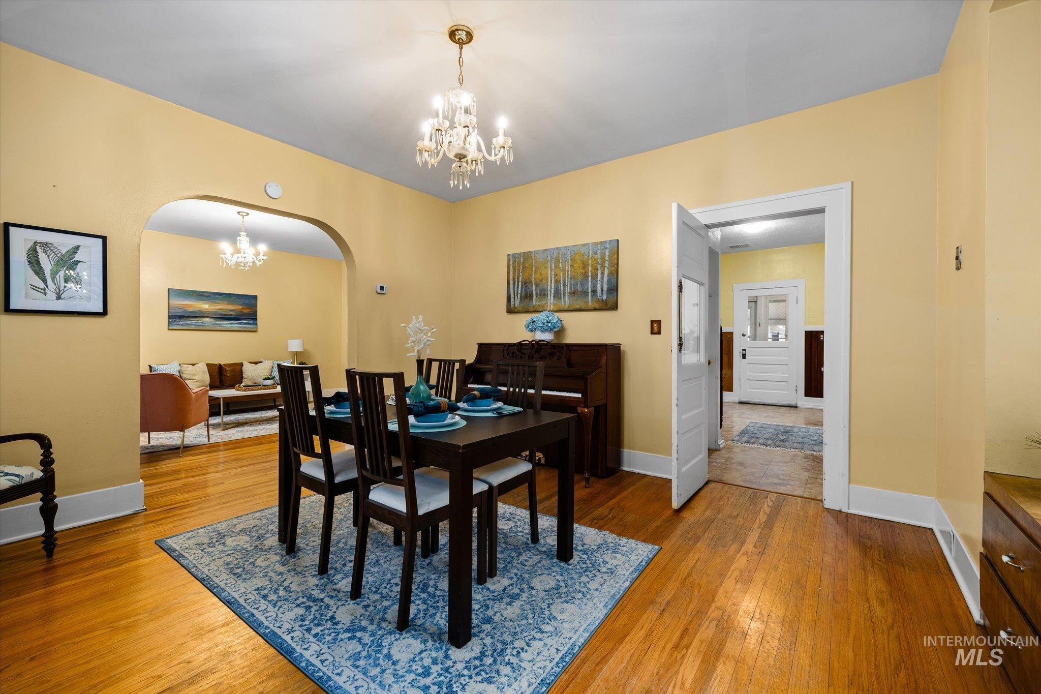 Dining space with arched walkways, a chandelier, and light wood-style floors
