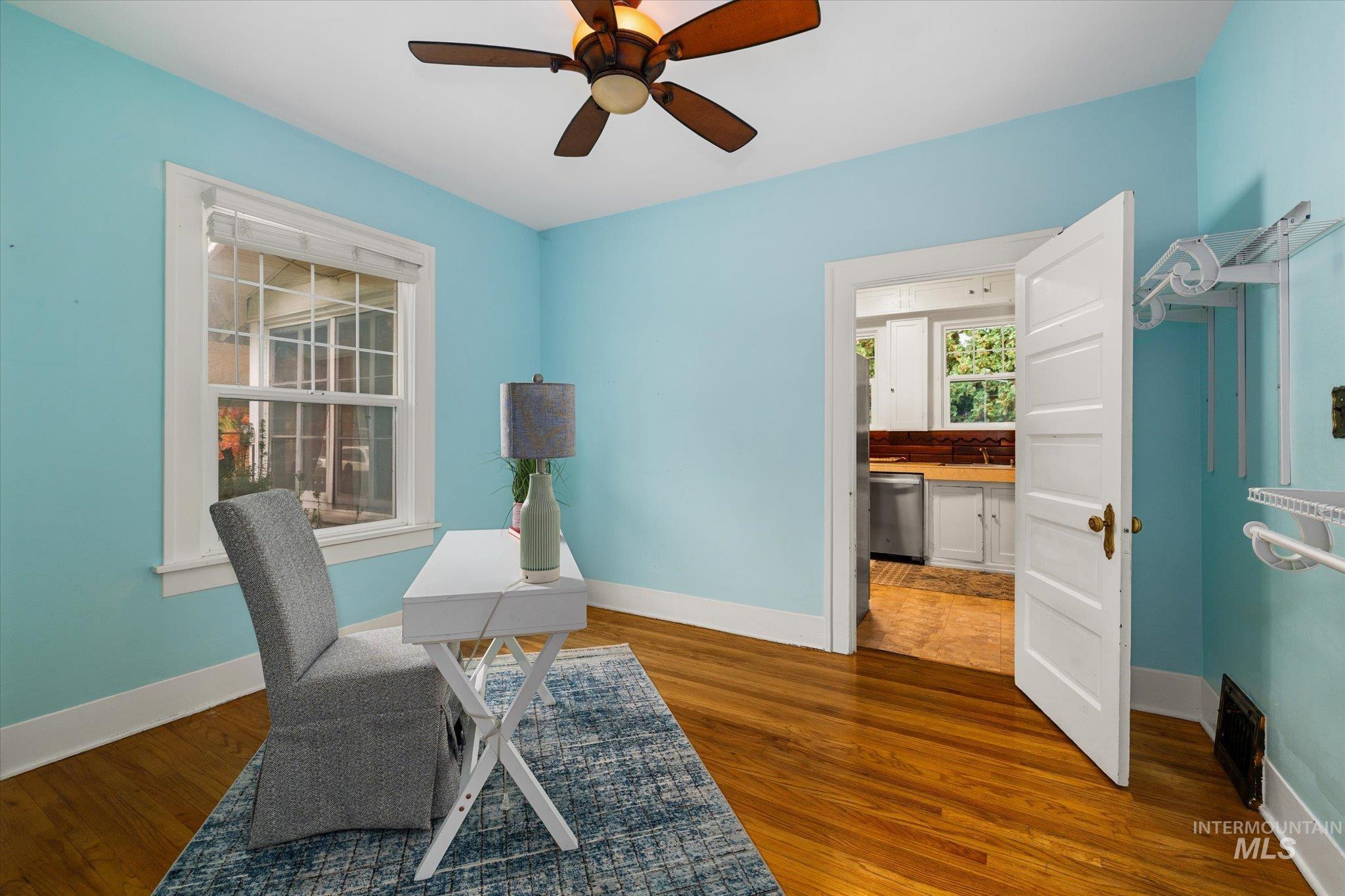 Office area with dark wood-style flooring and a ceiling fan