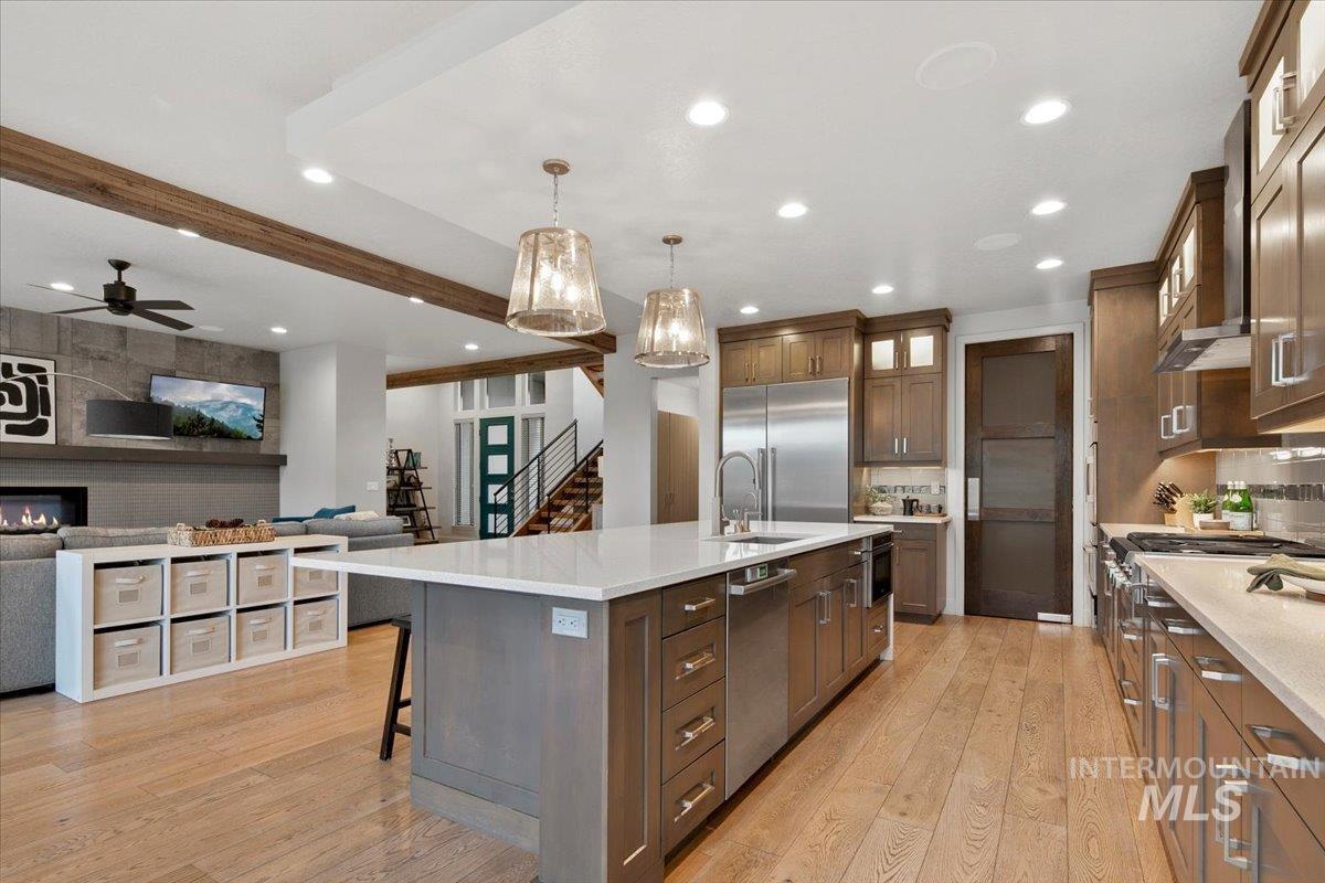 Kitchen featuring open floor plan, recessed lighting, glass insert cabinets, hanging light fixtures, and a large island with sink