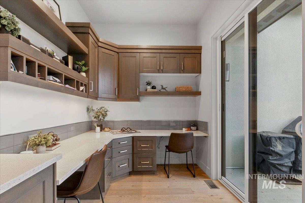 Office space with built in desk and light wood-style flooring