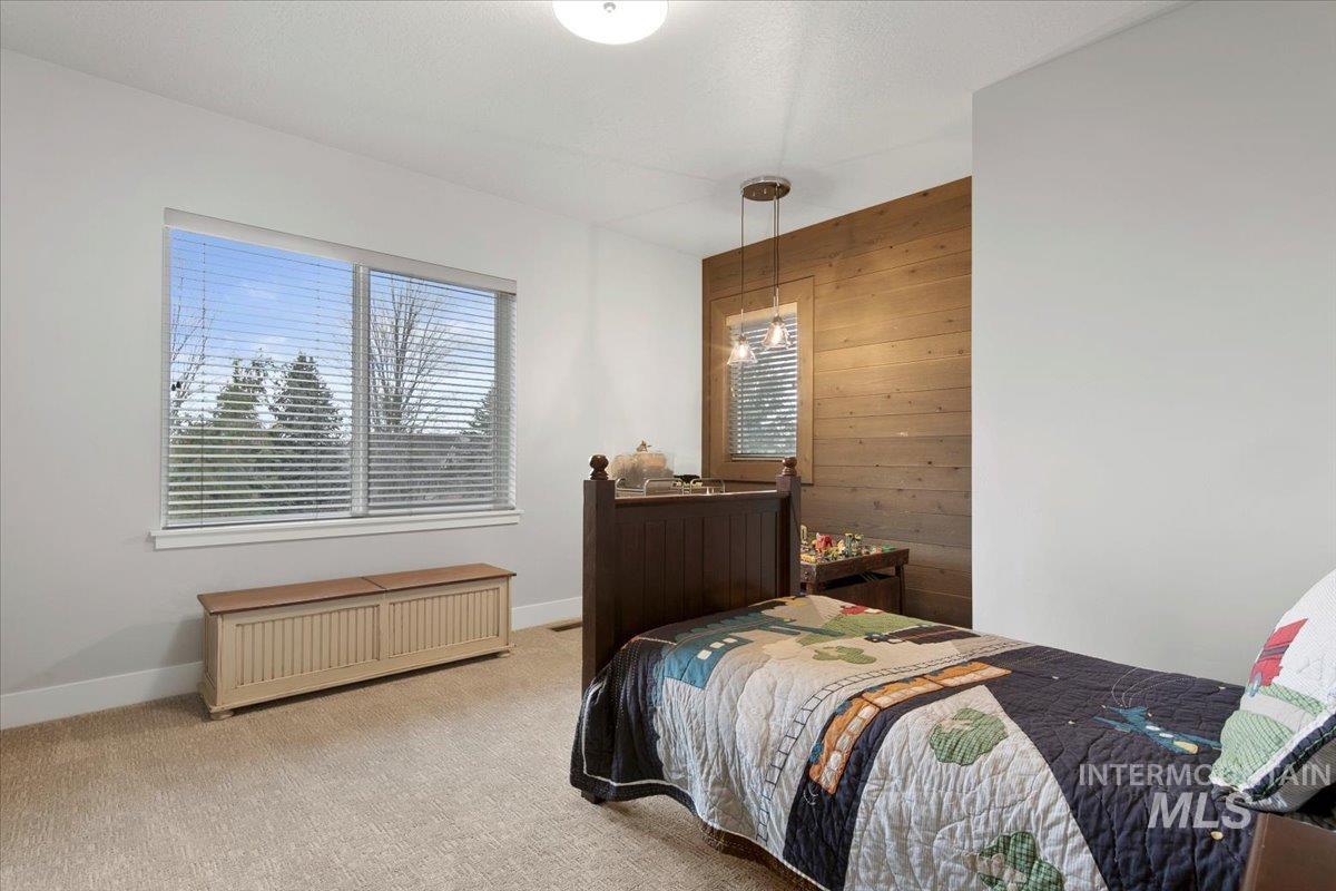 Bedroom featuring multiple windows, wooden walls, and carpet