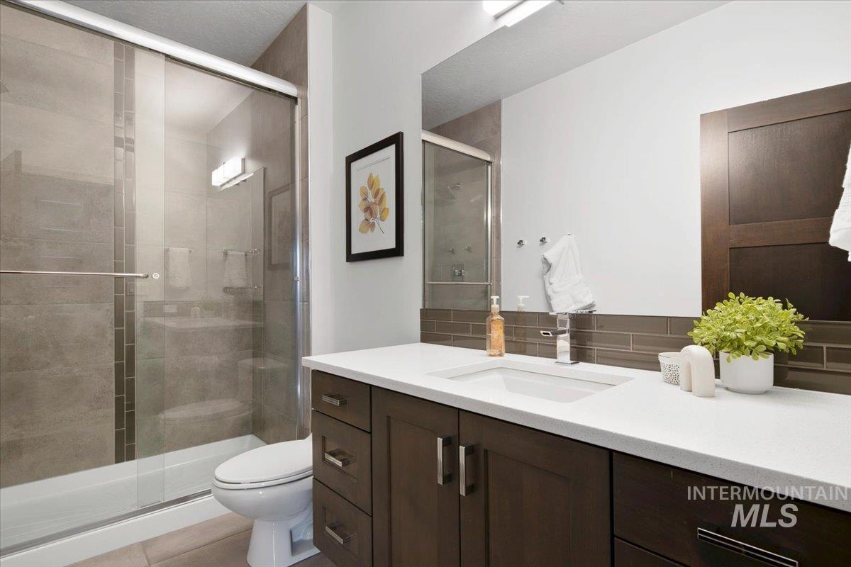 Full bath featuring vanity, a shower stall, decorative backsplash, and light tile patterned flooring